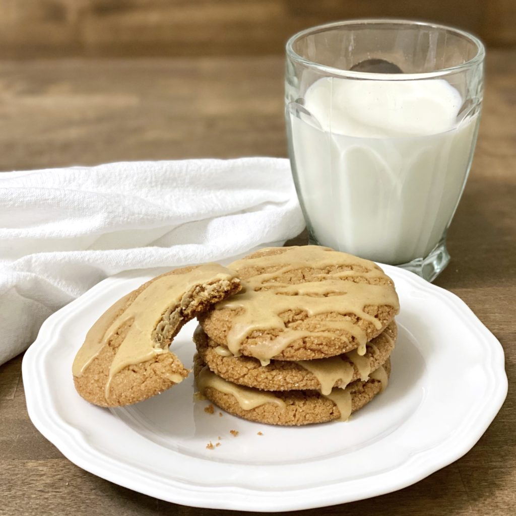 Pumpkin Spice cookies on a white plate with a glass of milk next to them.