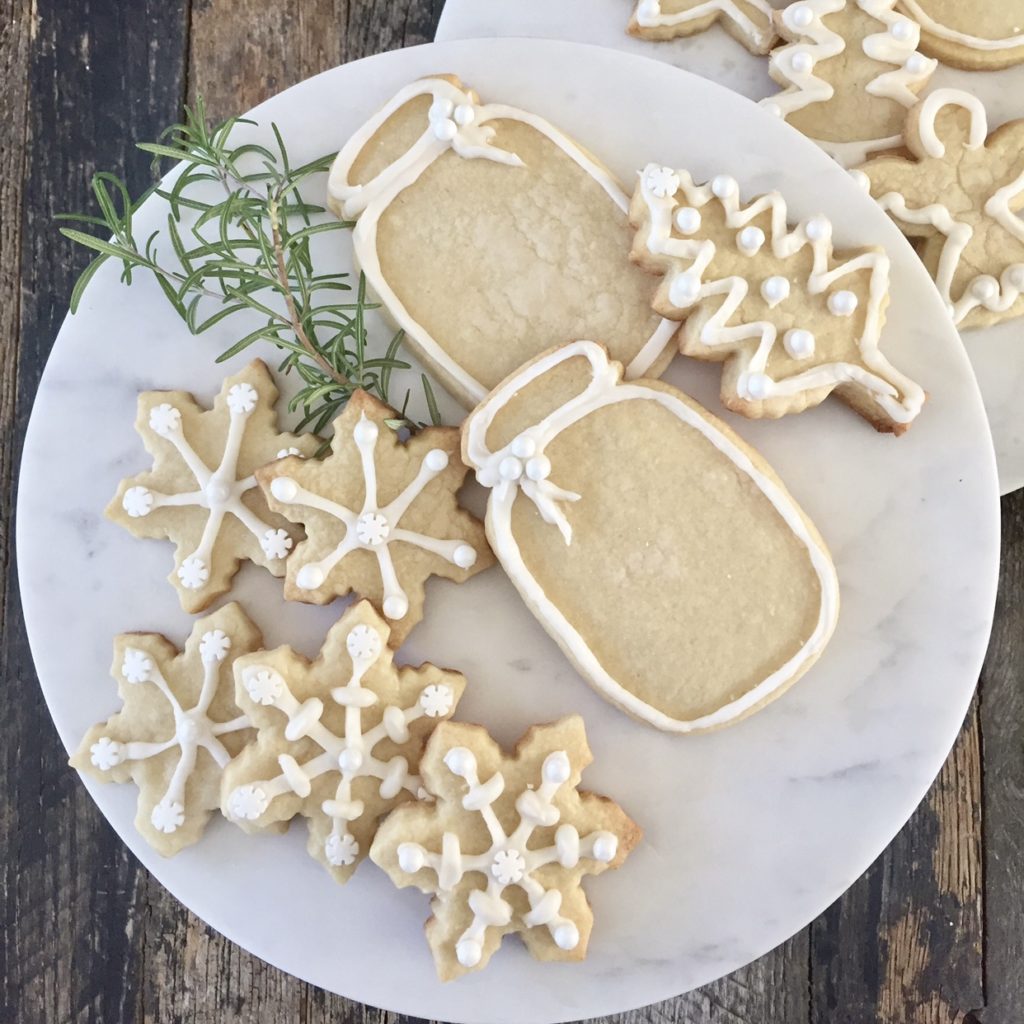Christmas shaped sugar cookies with white royal icing around them.
