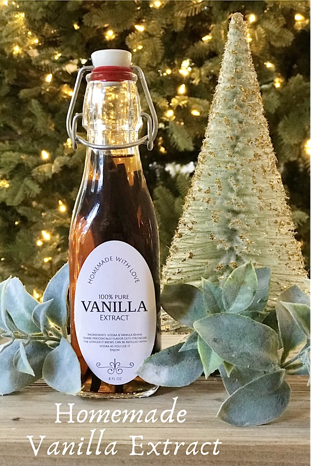 A bottle of homemade vanilla extract on the table in front of a Christmas tree.  