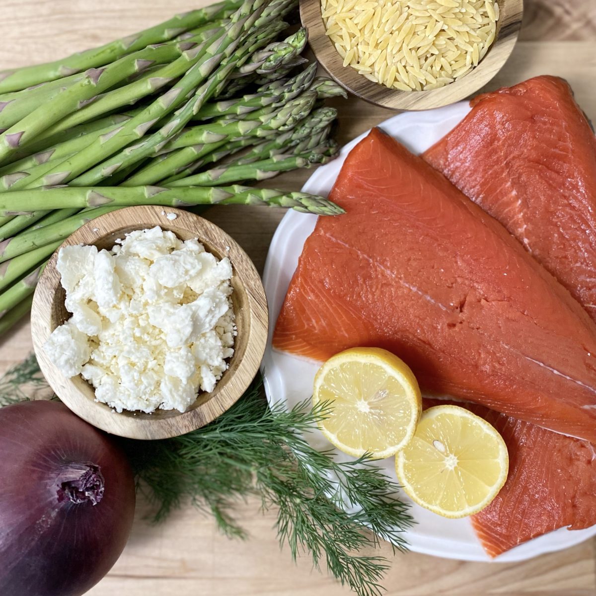 Ingredients for salmon, asparagus, and dill orzo salad including, salmon, fresh dill, asparagus, lemon, feta cheese, and orzo.