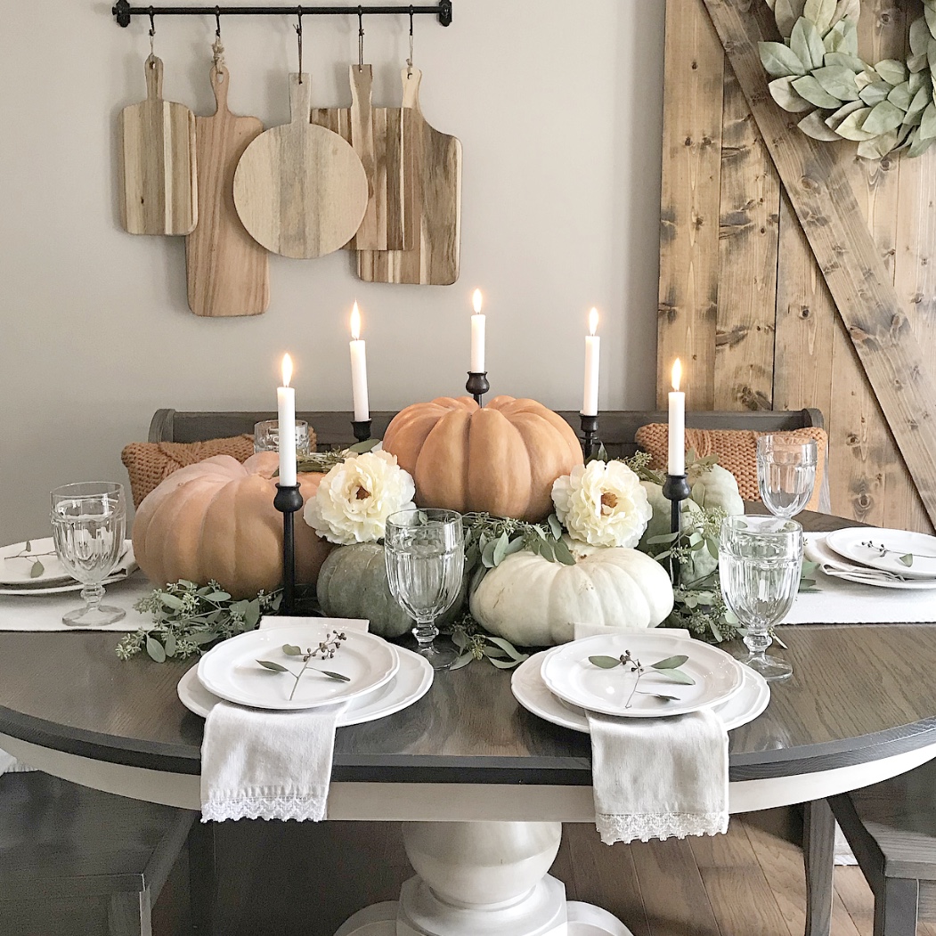 Table set for Fall with pumpkins, candles, and flowers.
