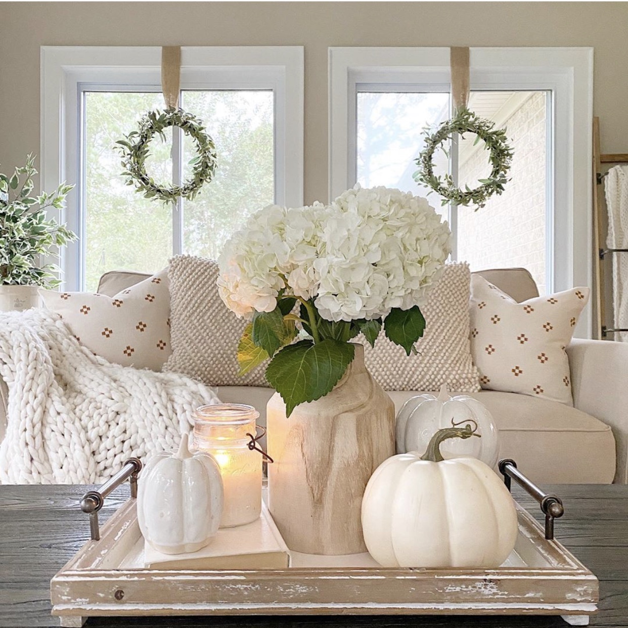 Tray styled on coffee table with wood vase, Fall faux stems, ceramic white pumpkins and a candle.