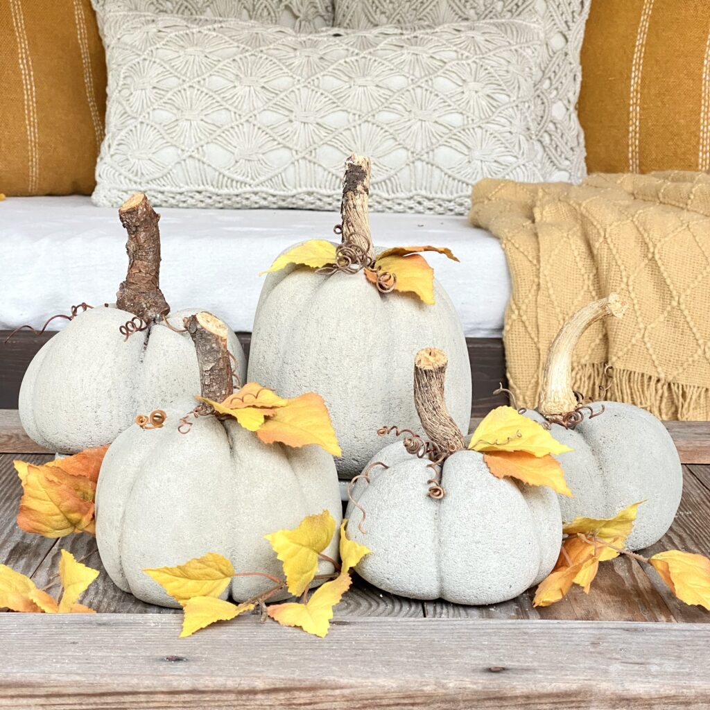Concrete pumpkins displayed on a coffee table with fall leaves. 