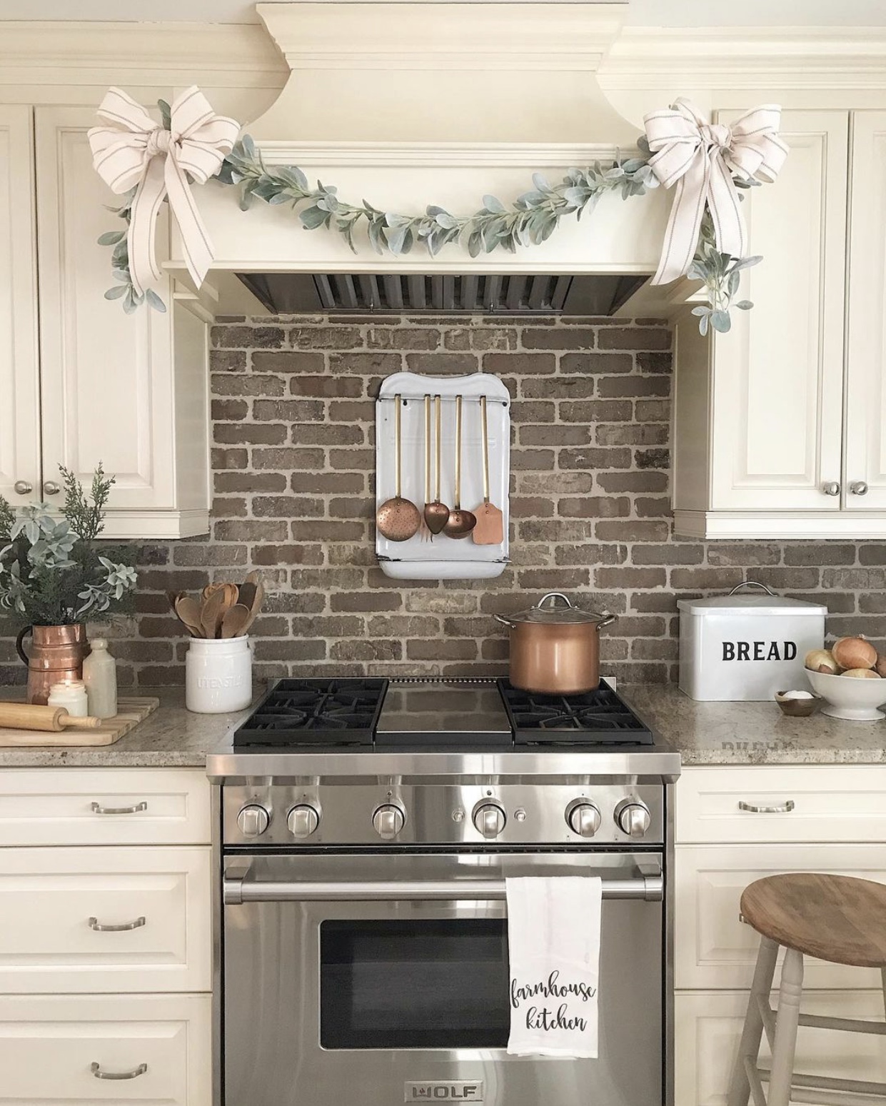 Farmhouse Christmas decor in the kitchen with garland over the stove hood and greenery in a vase.