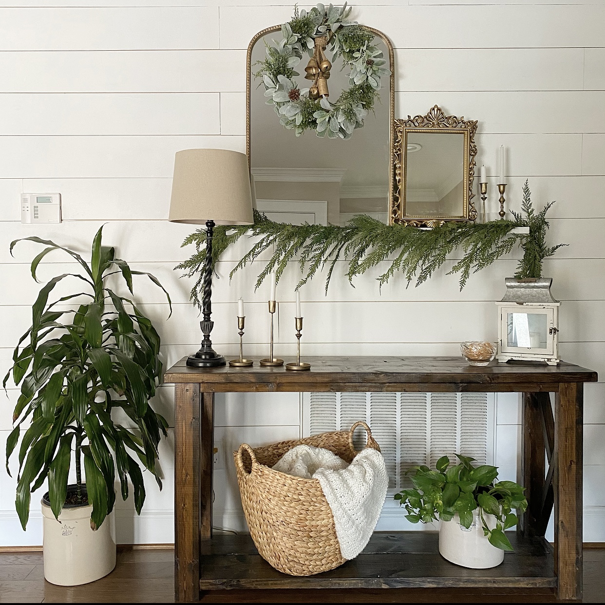 Foyer table decorated for winter using greenery and plants.