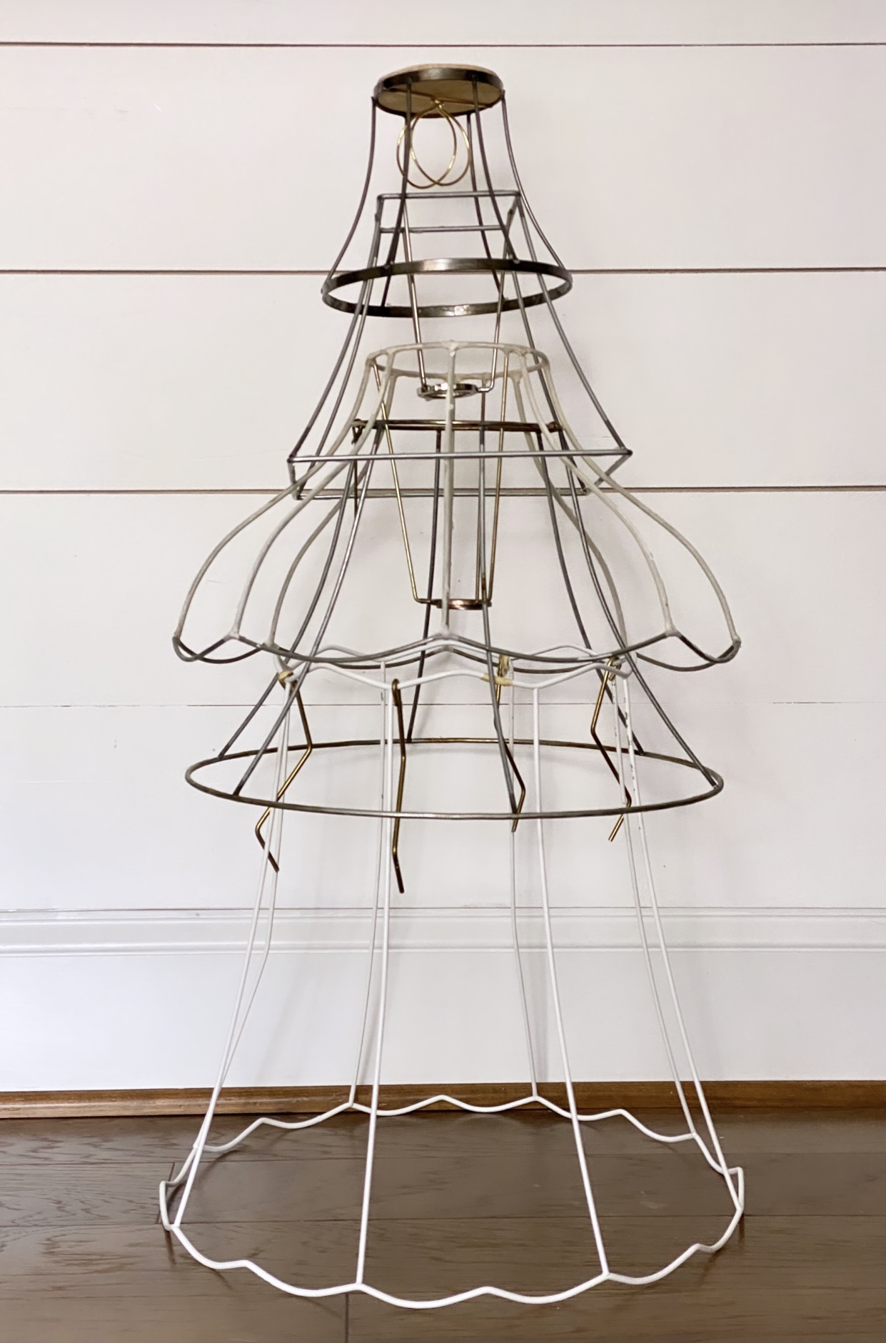 Six lampshade frames stacked on top of one another creating the form of a Christmas tree.