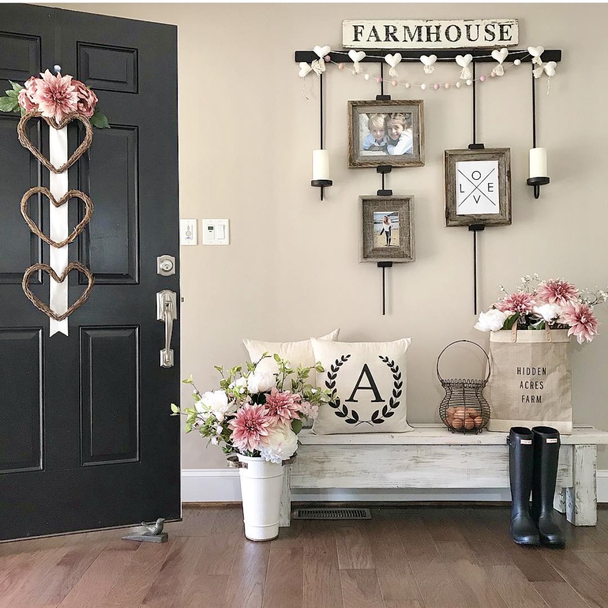 Valentine's Day touches in the farmhouse foyer including pink flowers and a heart door hanger.