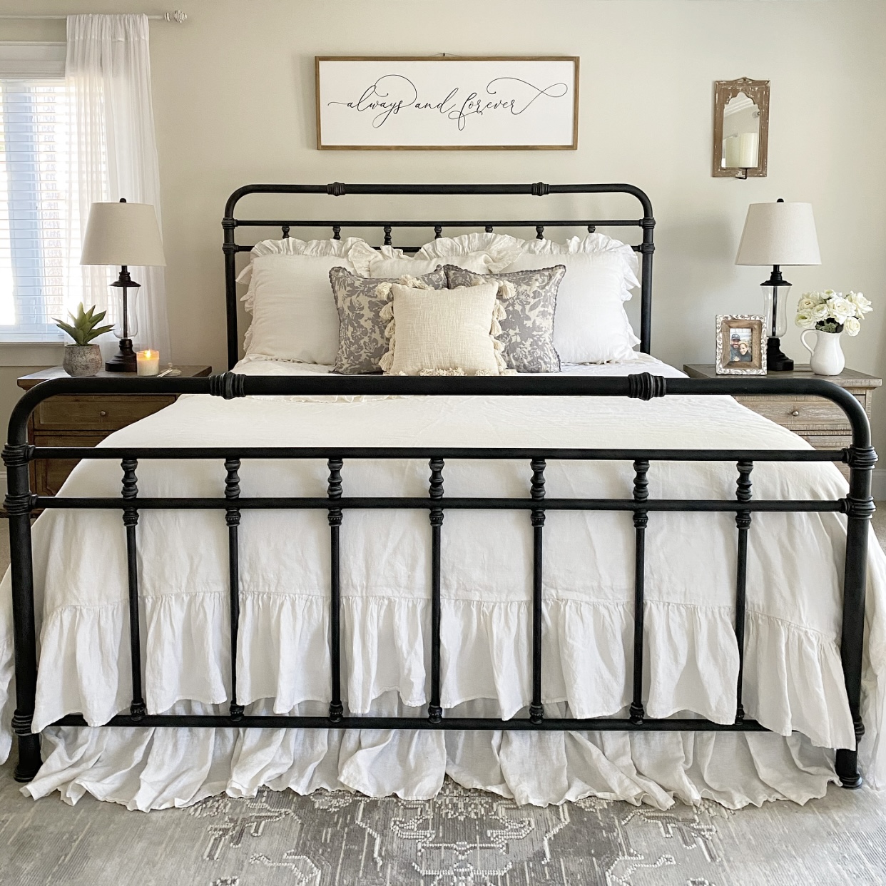 Bedroom view with white bedding on an iron bed and nightstands with the perfect bedside essentials.