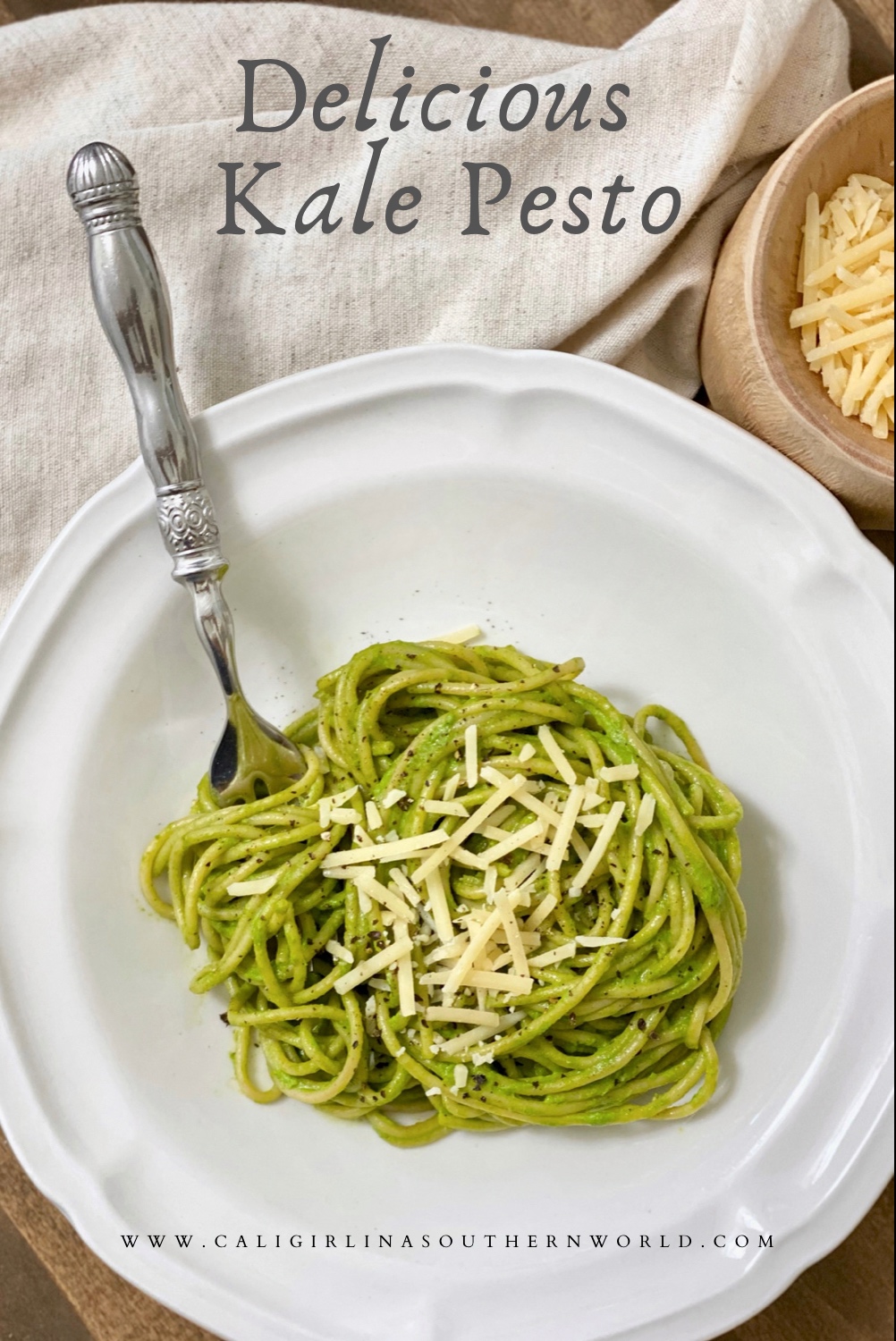 Pinterest image. Delicious kale pesto on whole wheat spaghetti pasta with parmesan cheese and fresh cracked pepper on top served in a white pasta bowl.