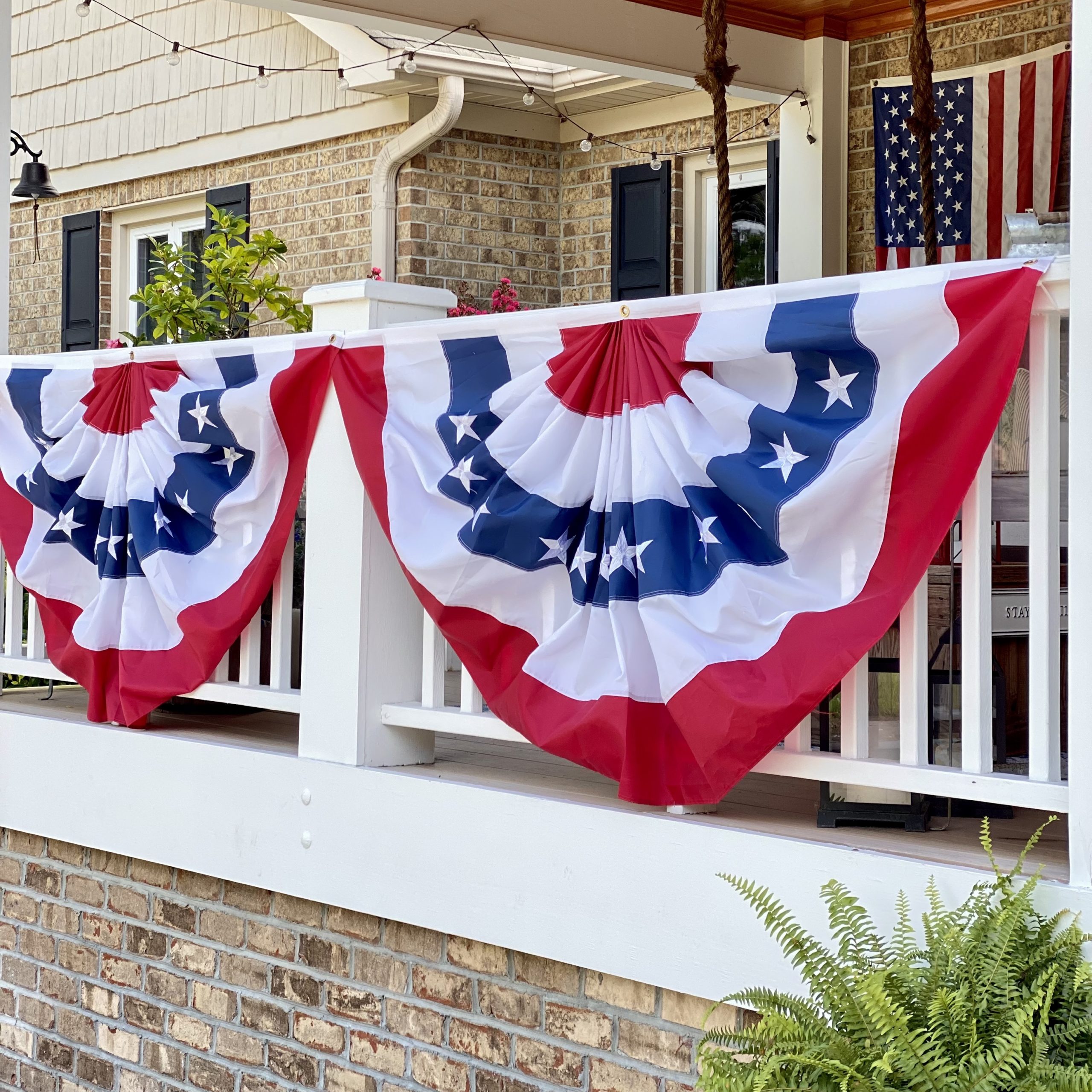 Pleated red, white, and blue bunting on the front porch railings. 