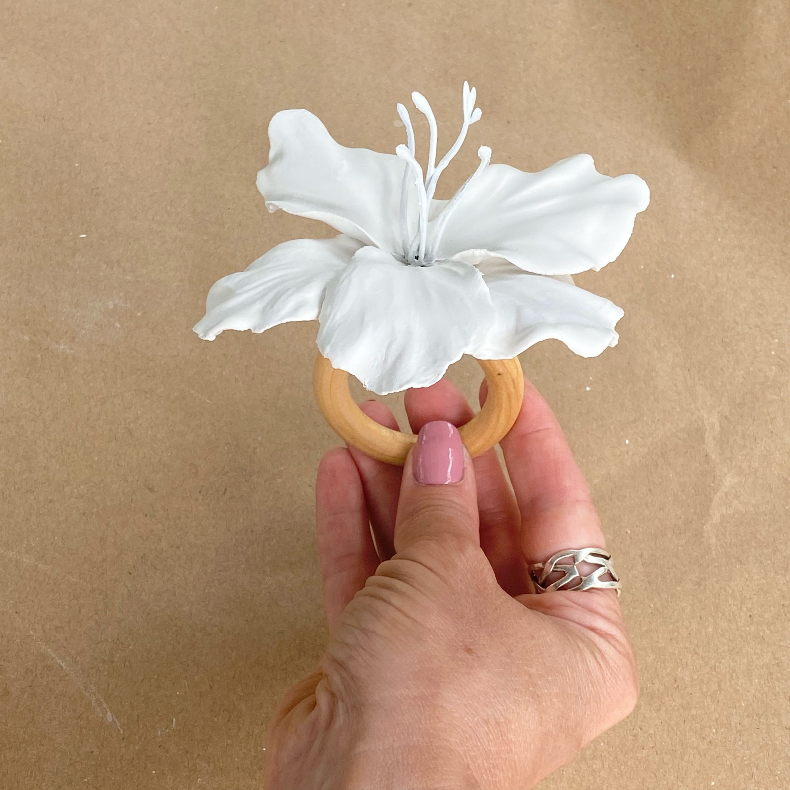 A hand holding up a completed plaster of paris floral napkin ring.