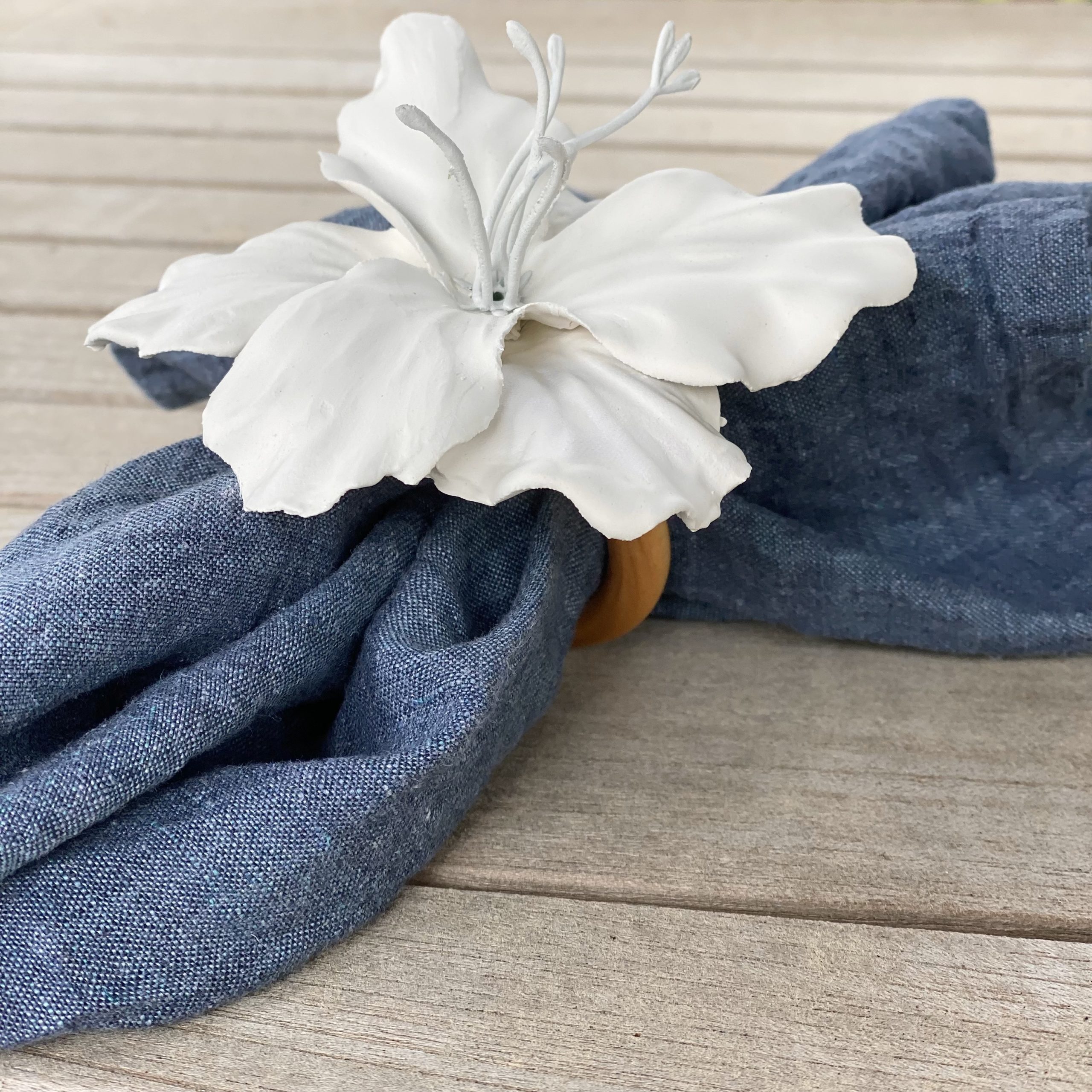 Plaster of paris floral napkin ring with a blue linen napkin in it.