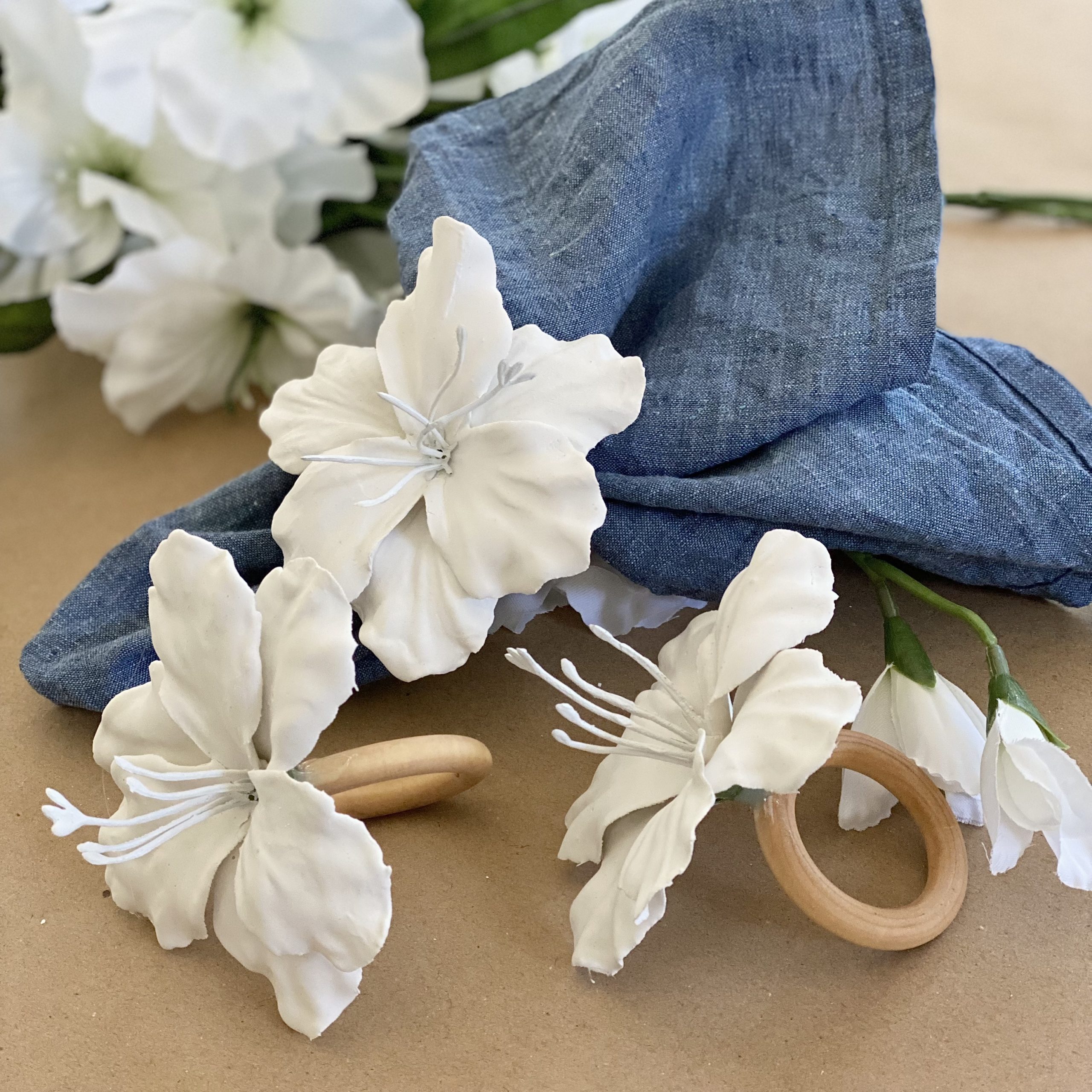 Plaster of paris floral napkin ring with a blue linen napkin in it and other napkin rings around it..