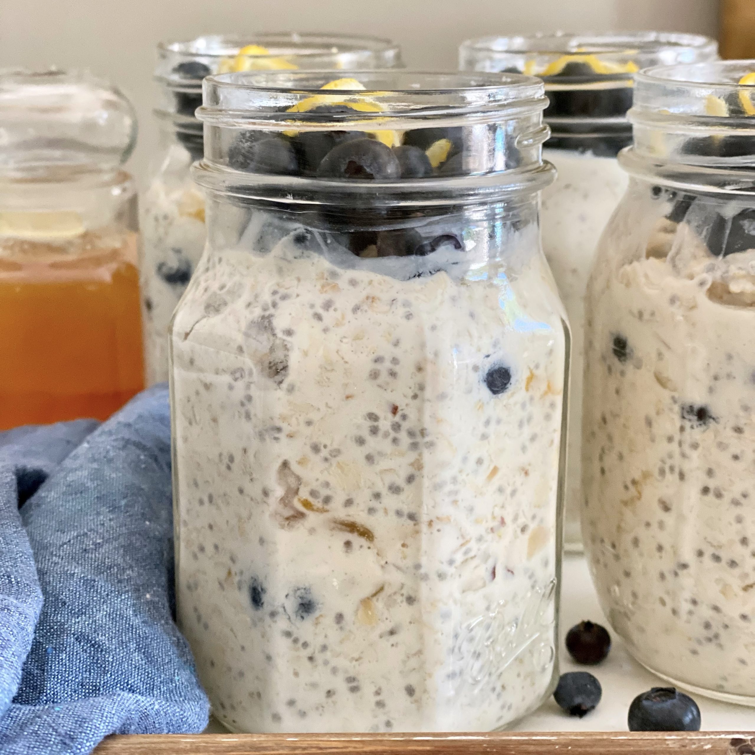 Overnight oats in a glass jar on a tray with a blue napkin and honey.