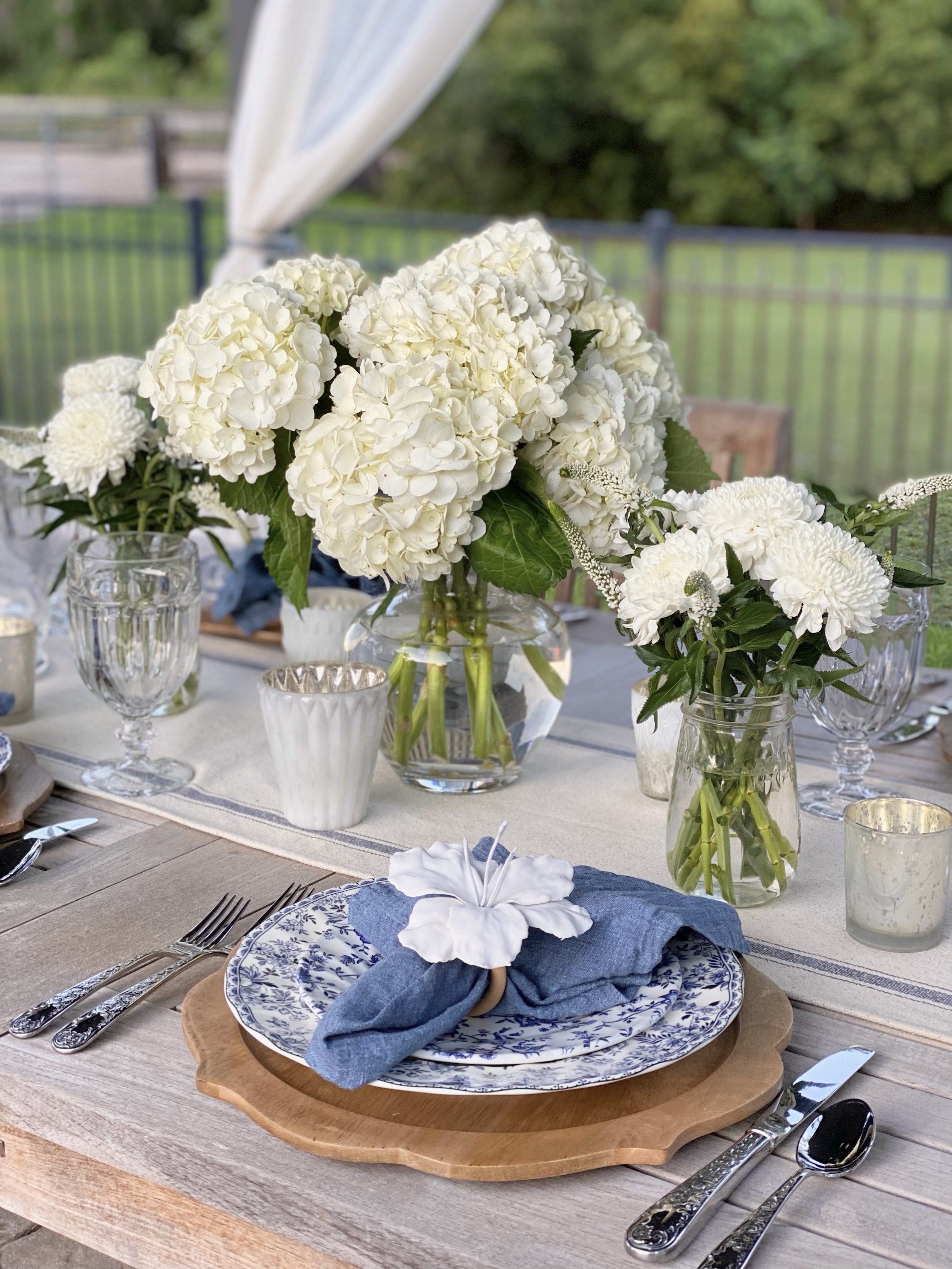 Blue and white tablescape with white floral arrangement centerpieces.