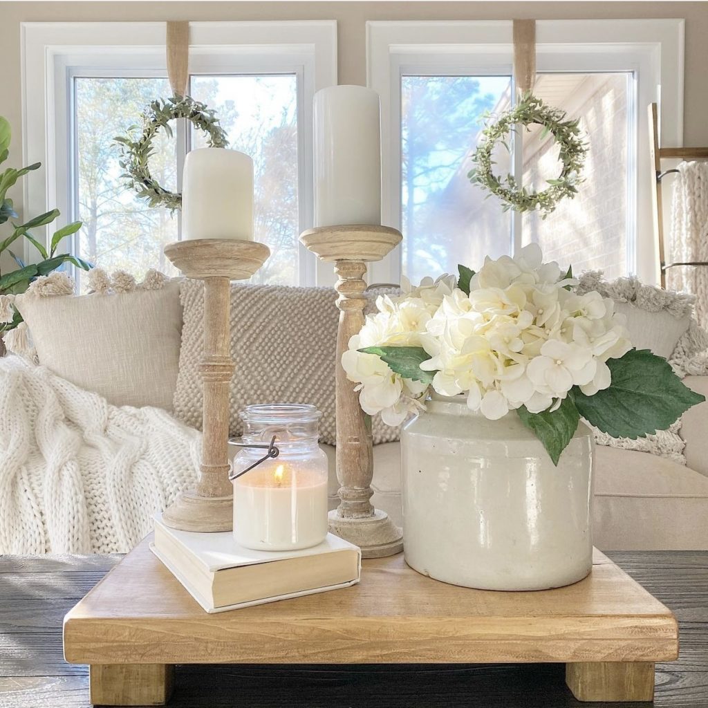 DIY wood riser styled with a crock of hydrangeas, candlesticks, and a vintage book in the living room.