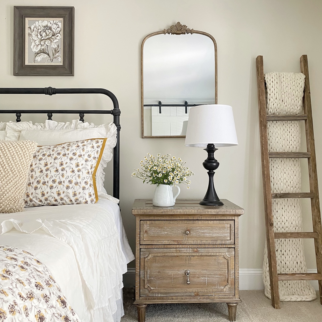 Summer Farmhouse Bedroom Inspiration including linens, a nightstand, flowers, a lamp, a mirror and a rustic blanket ladder.
