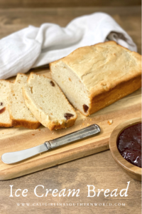 Ice Cream Bread on a bread board sliced with a wood bowl of strawberry jam and a knife next to it.