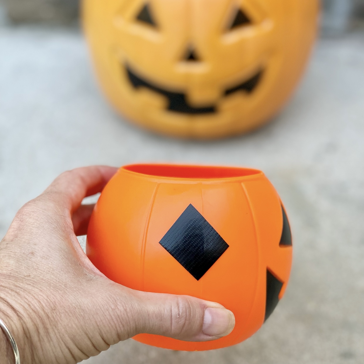 Mini plastic jack o'lantern with holes in the side covered with duct tape.