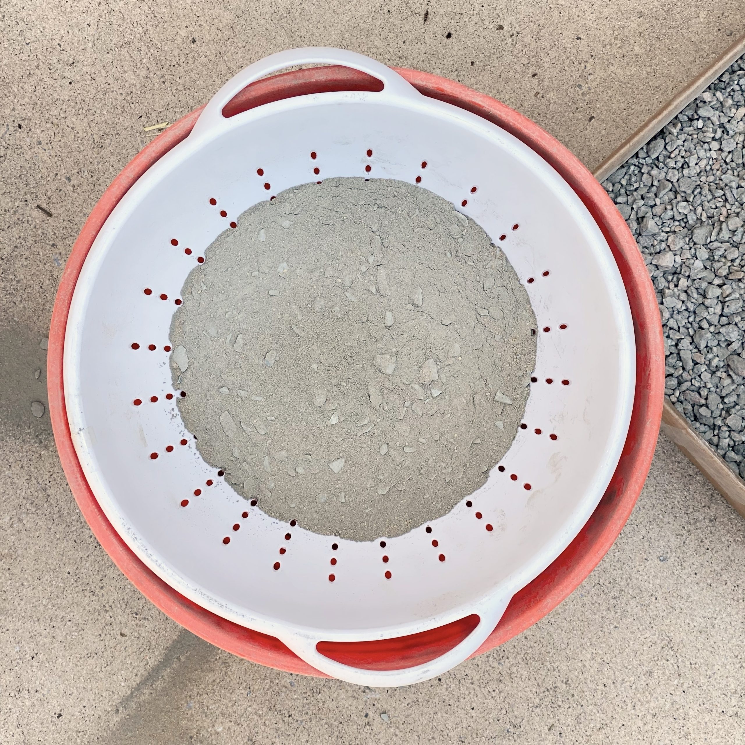 Rocks being sifted out of concrete in colander.