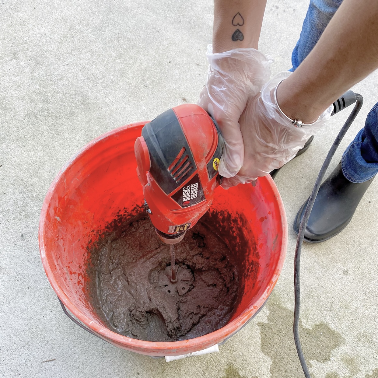 Mixing concrete in a large bucket with a concrete mixer on a drill.