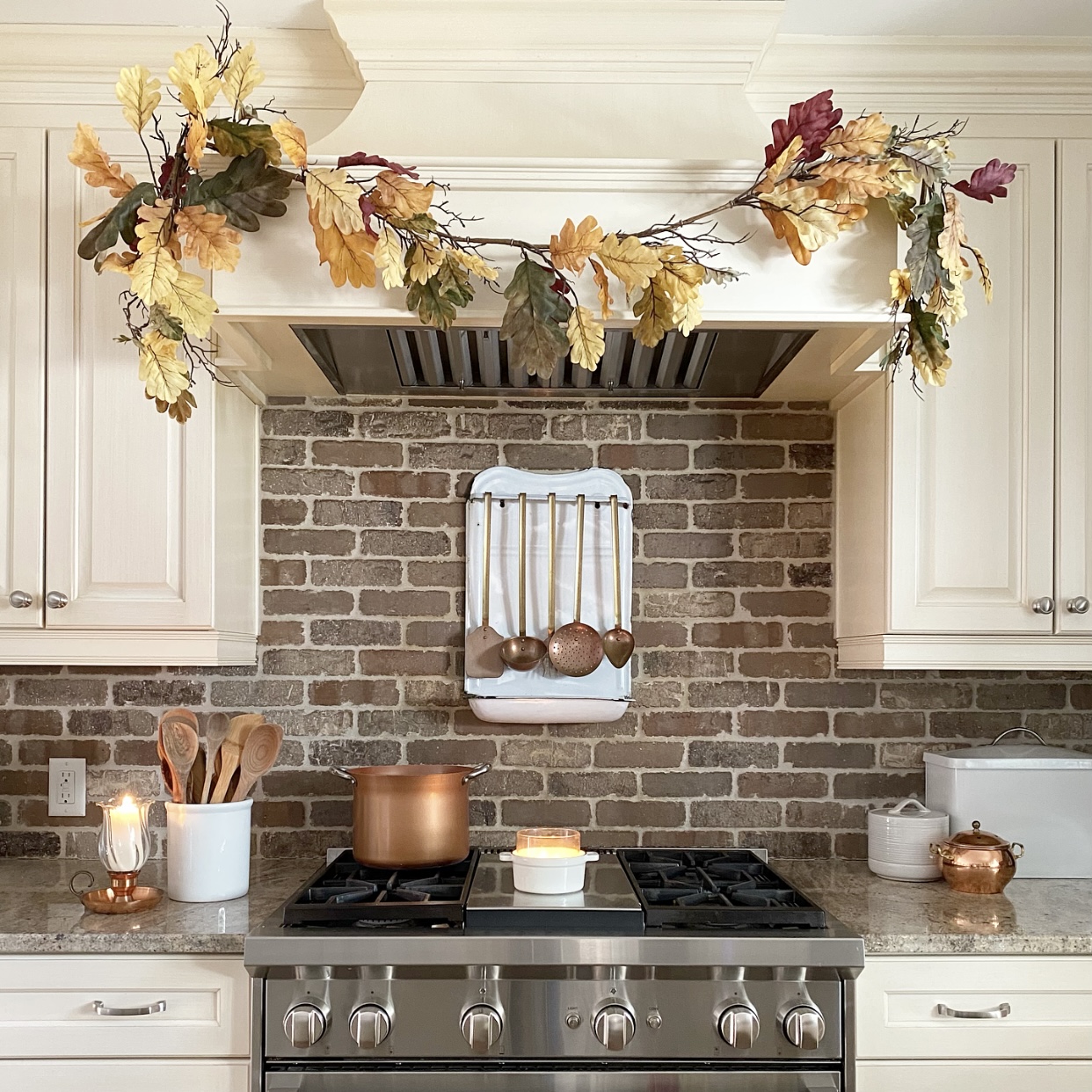 Kitchen hood with Fall garland on it. Candles and copper on and around the stove.
