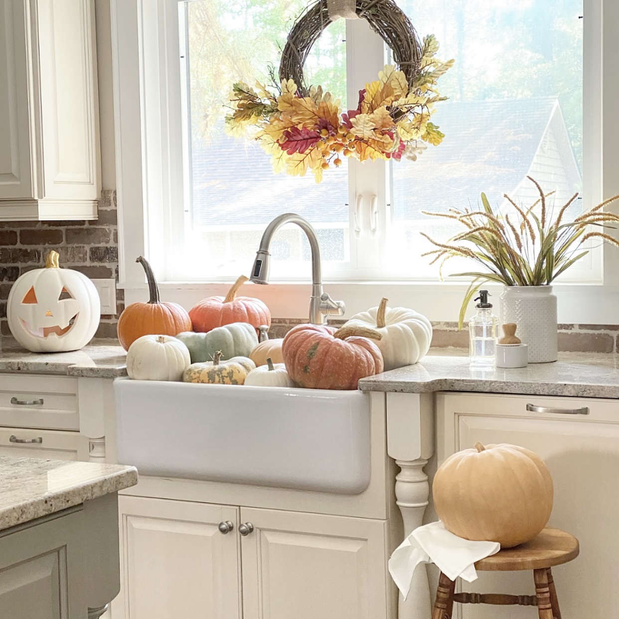Pumpkins in the farmhouse sink with a Fall wreath in the window. 