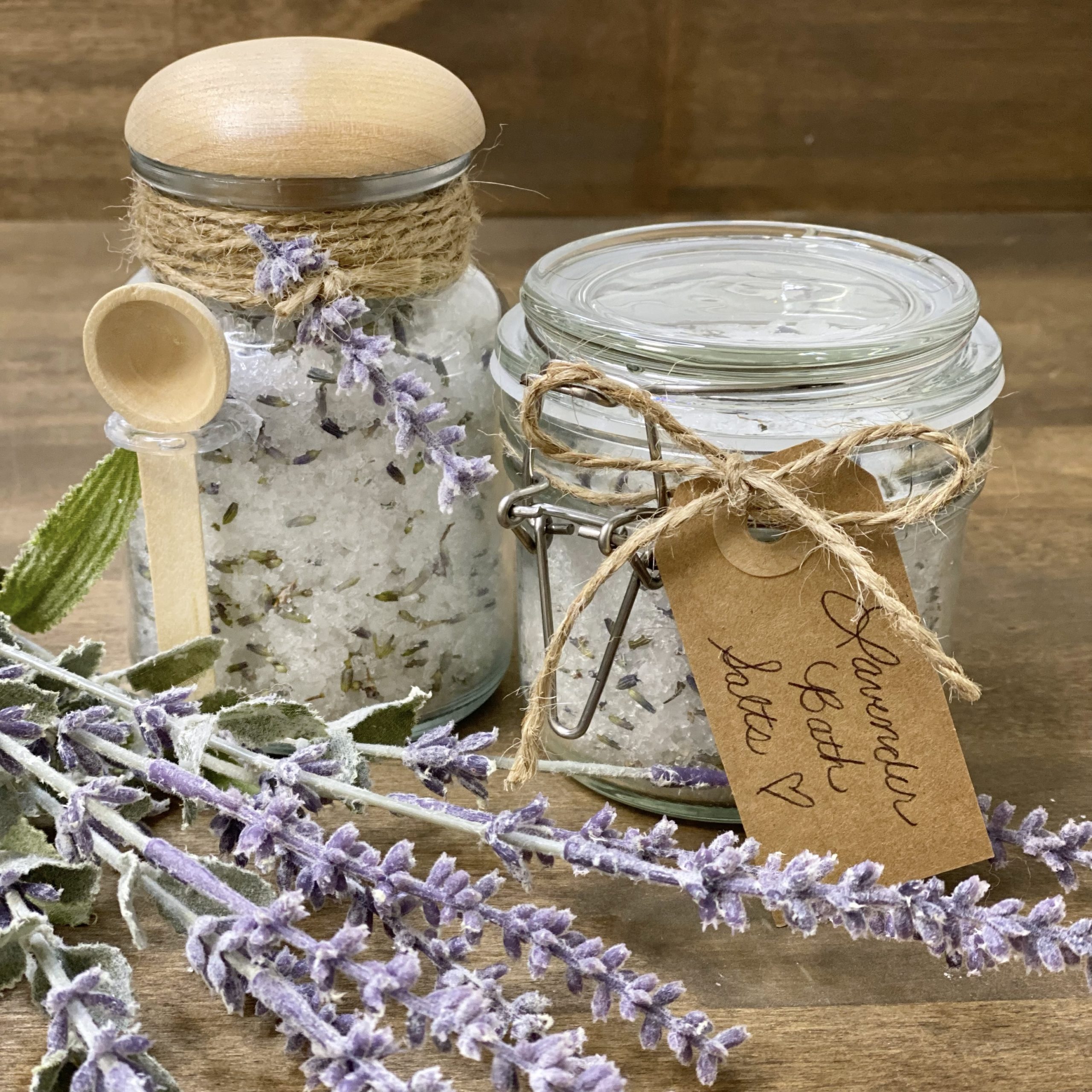 Homemade lavender bath salts in jars with lavender in the foreground.
