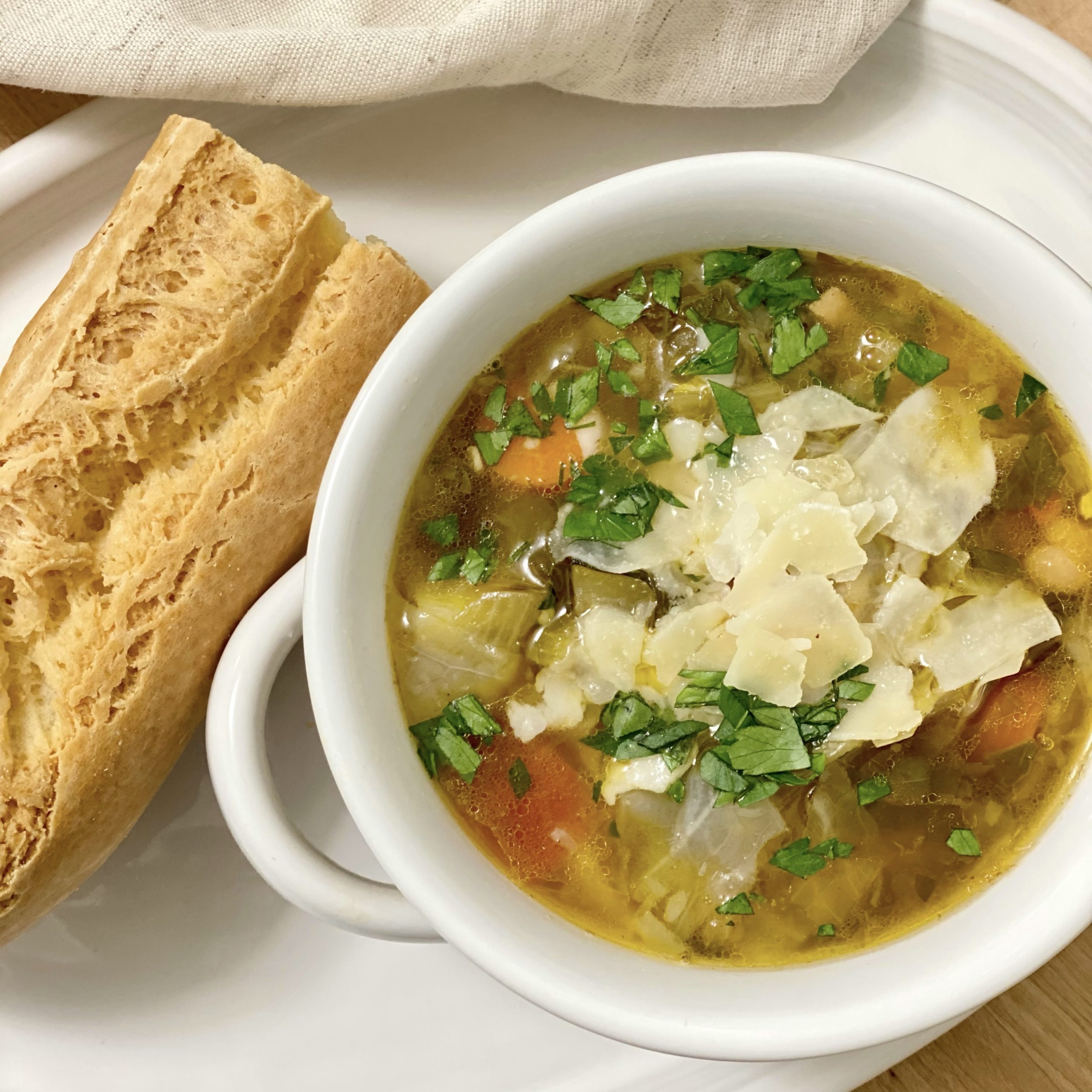 A bowl of minestrone soup with bread on the side.
