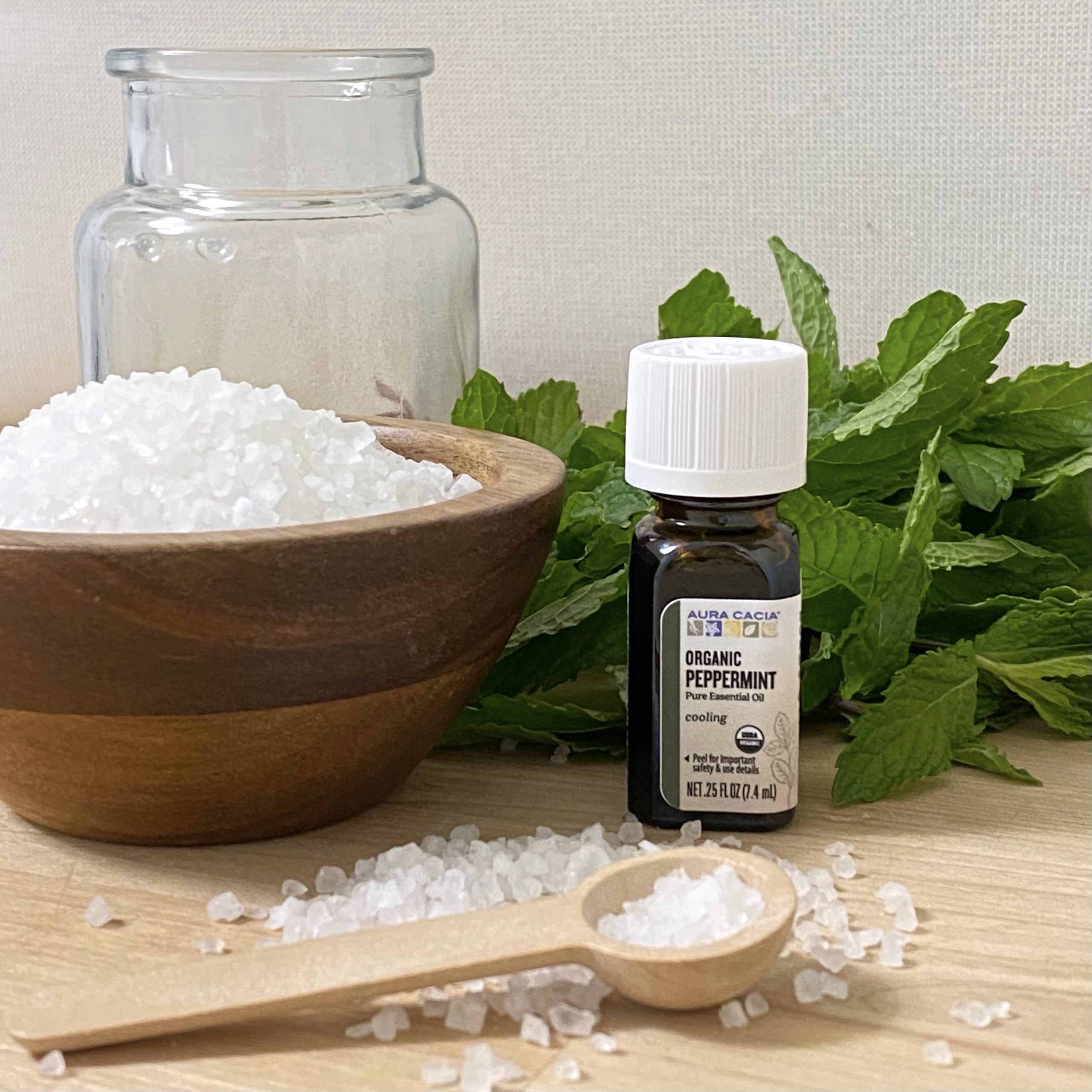 Everything you need to make peppermint bath salts including epsom salt, peppermint essential oil, peppermint, and a jar.