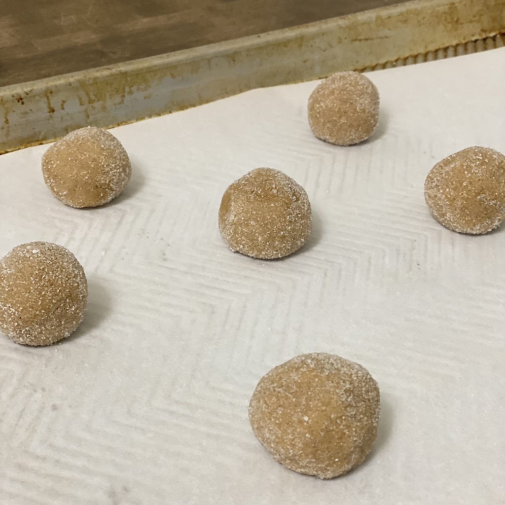 Pumpkin Spice Cookie dough balls rolled in sugar and placed on a baking sheet lined with parchment paper.