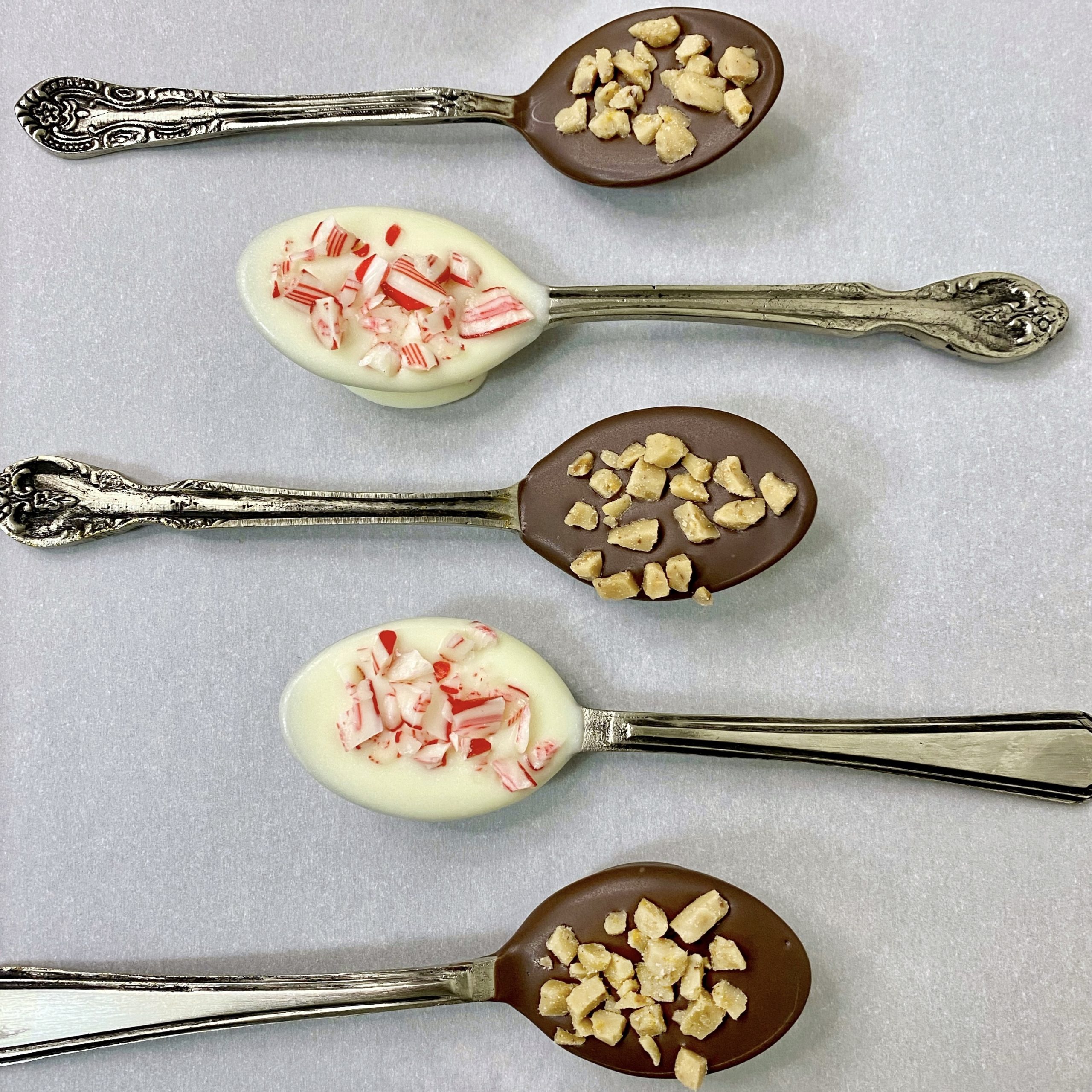 Chocolate dipped spoons on a tray with parchment paper.