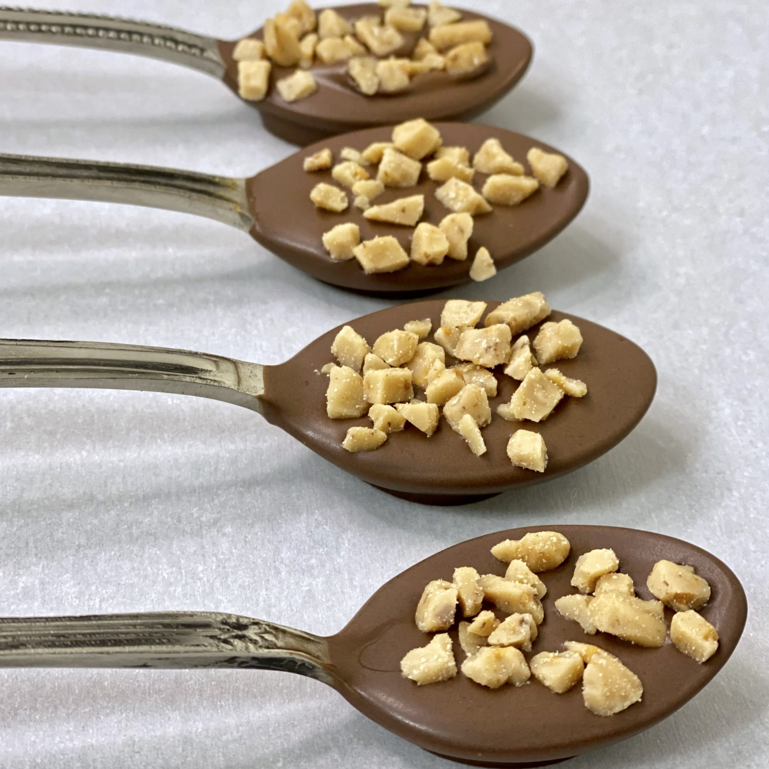 Chocolate dipped spoons with toffee bits on them.