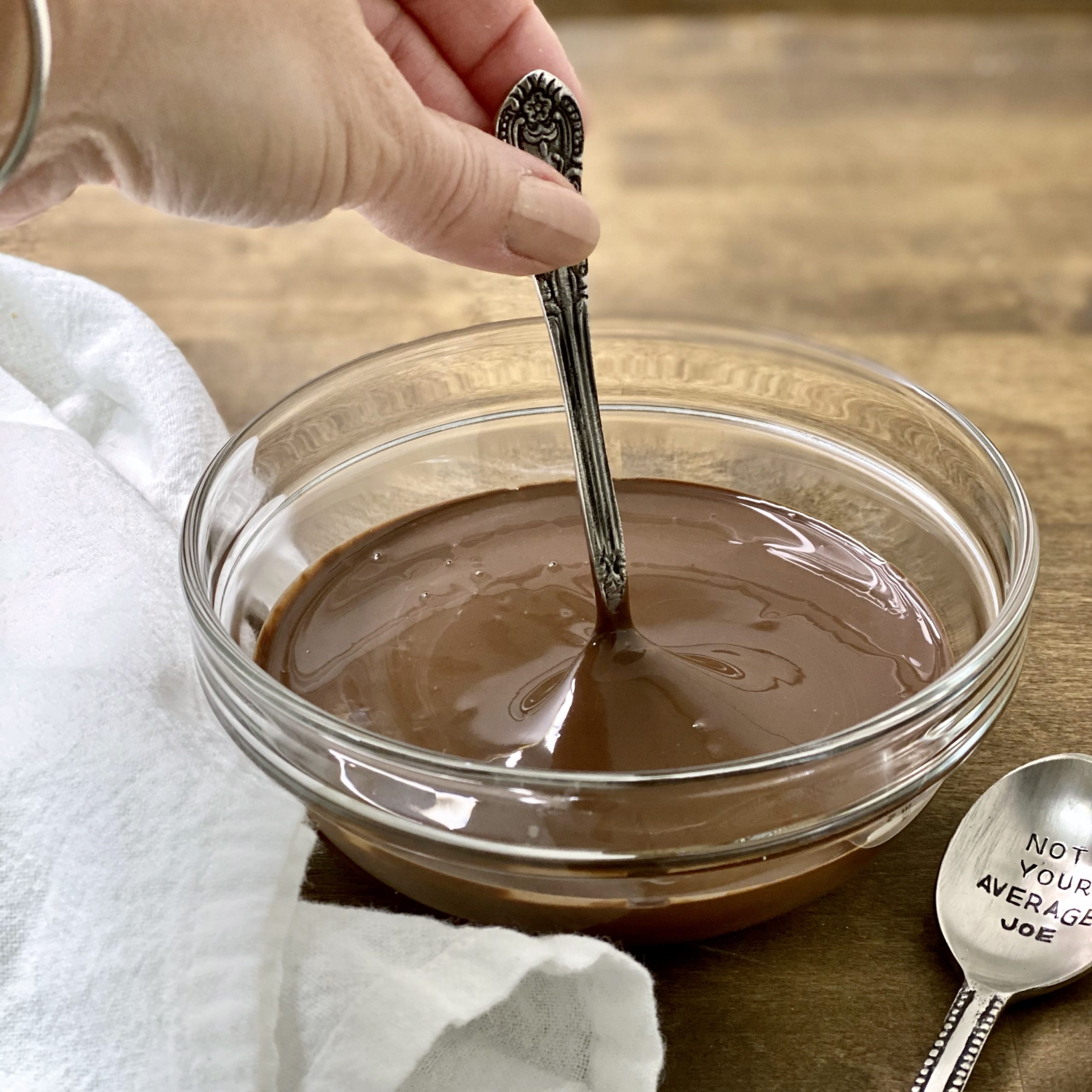 Dipping a spoon in melted dark chocolate.
