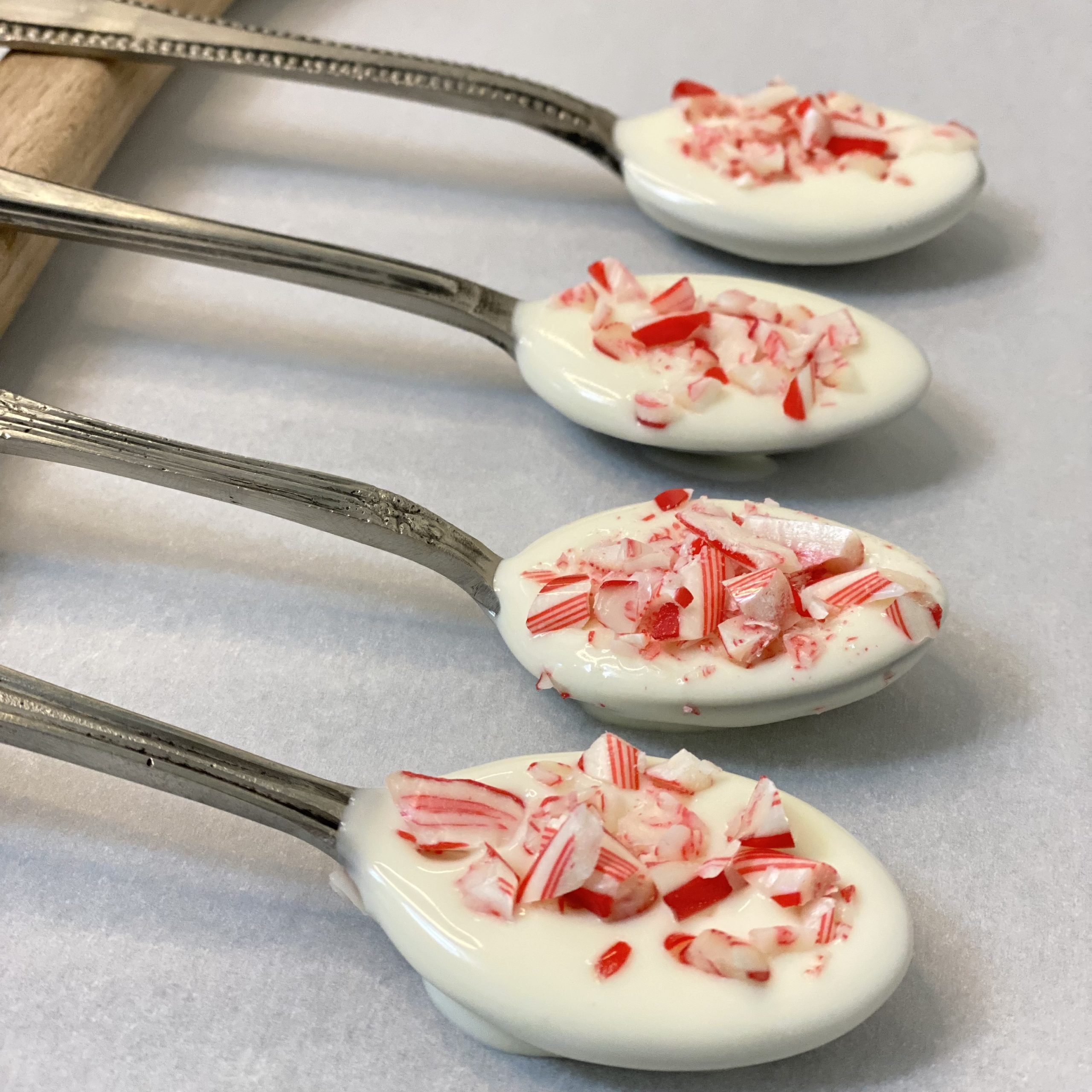Spoons dipped in white chocolate and crushed candy cane sprinkled on the chocolate.