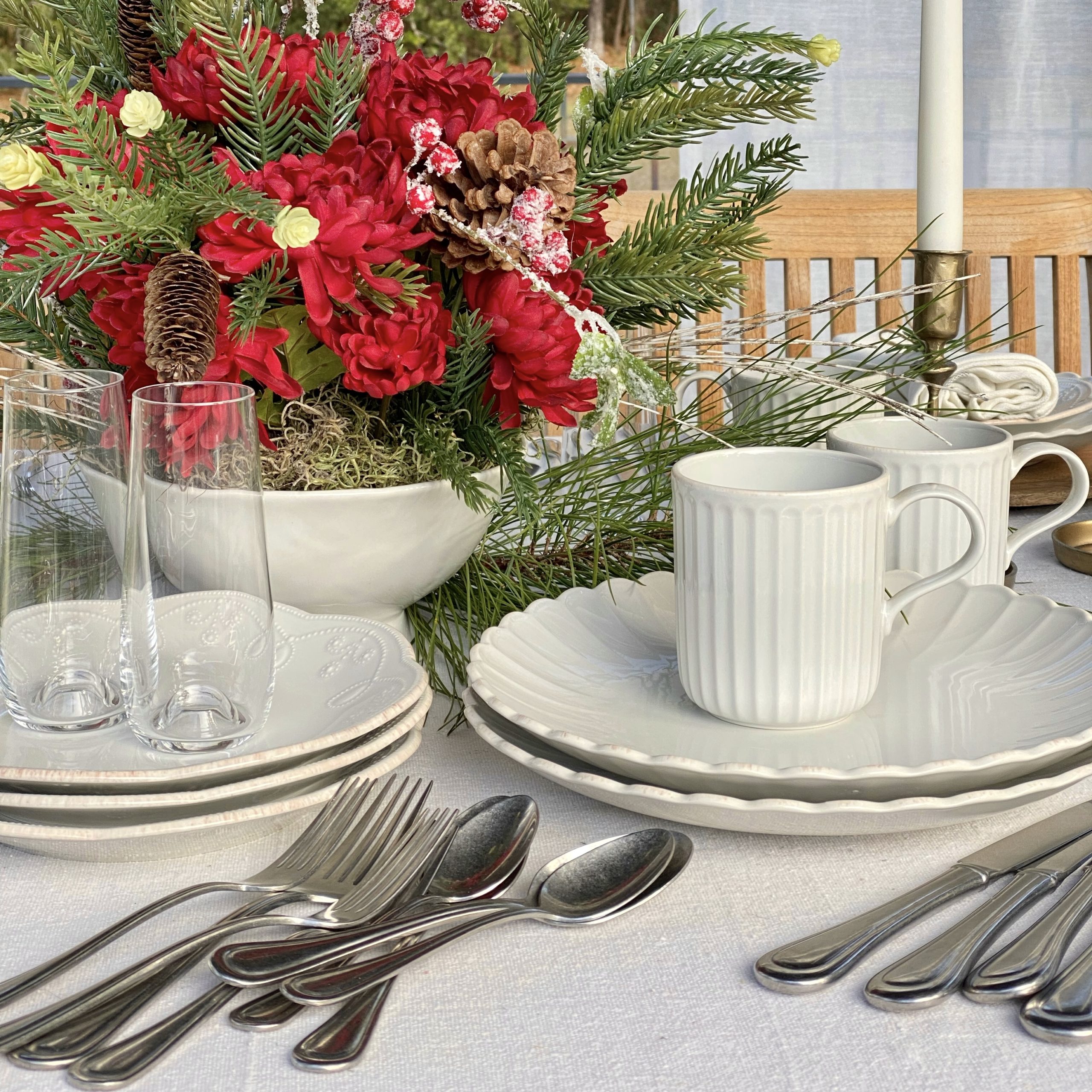 Lenox dishes and flatware set out on the table in front of the red floral centerpiece.