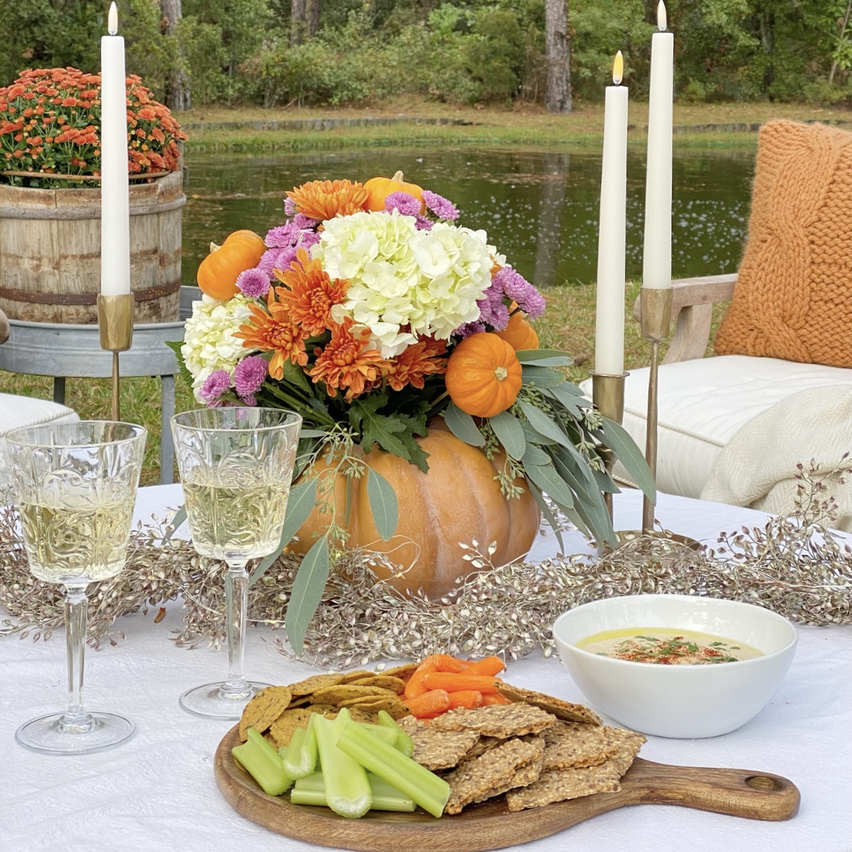 White bean hummus on the table with a fall floral arrangement, wine, and candles.