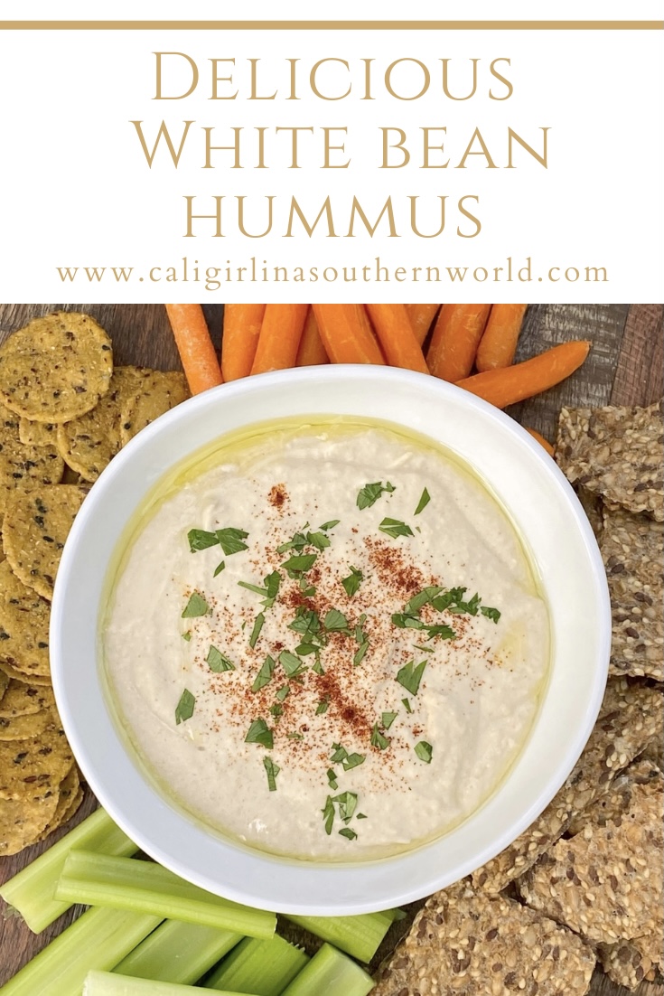 Pinterest Pin for delicious white bean hummus in a white bowl with crackers, celery sticks, and carrots around it. Perfect for a casual outdoor fall gathering.