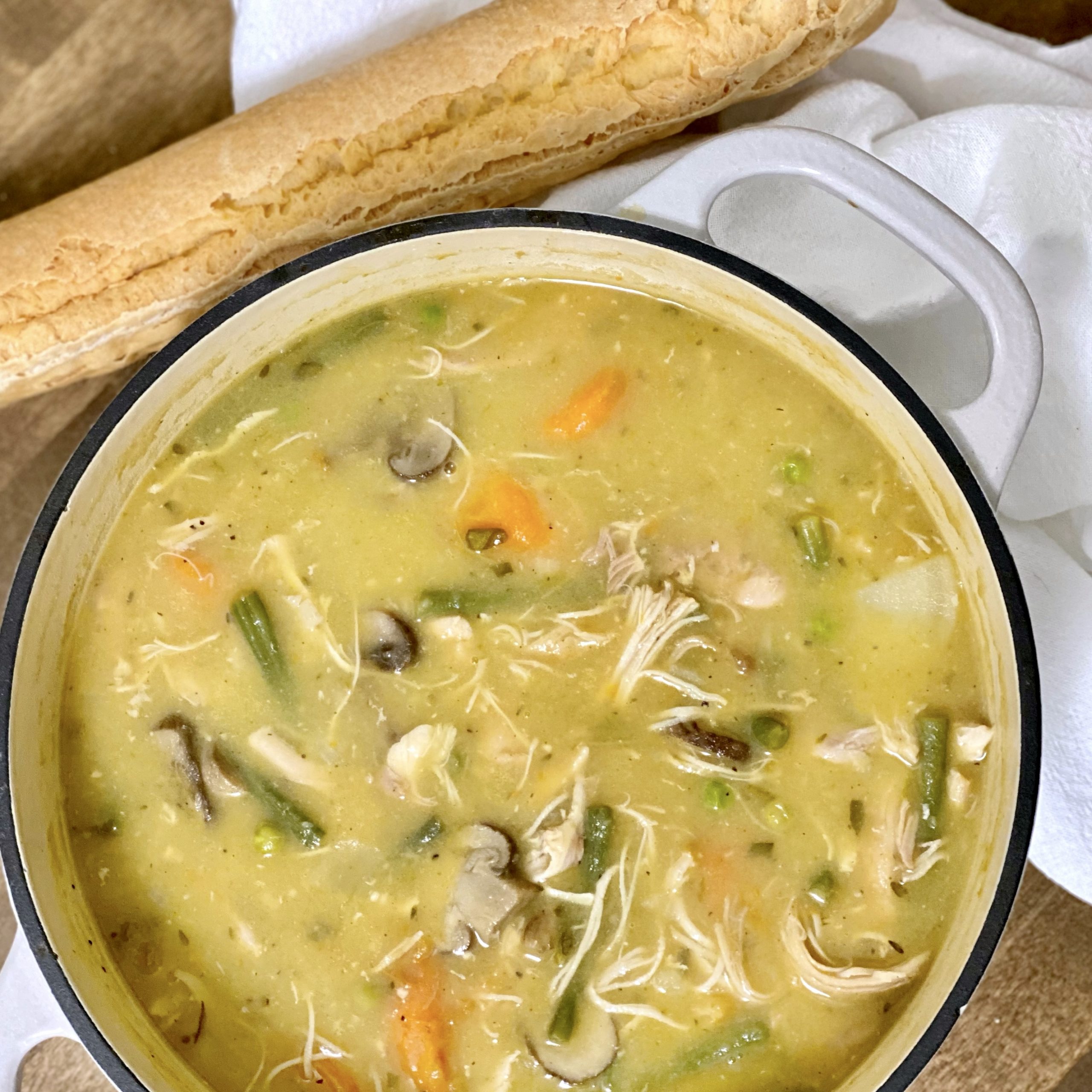 Savory Chicken Stew in a pot with a baguette next to it.