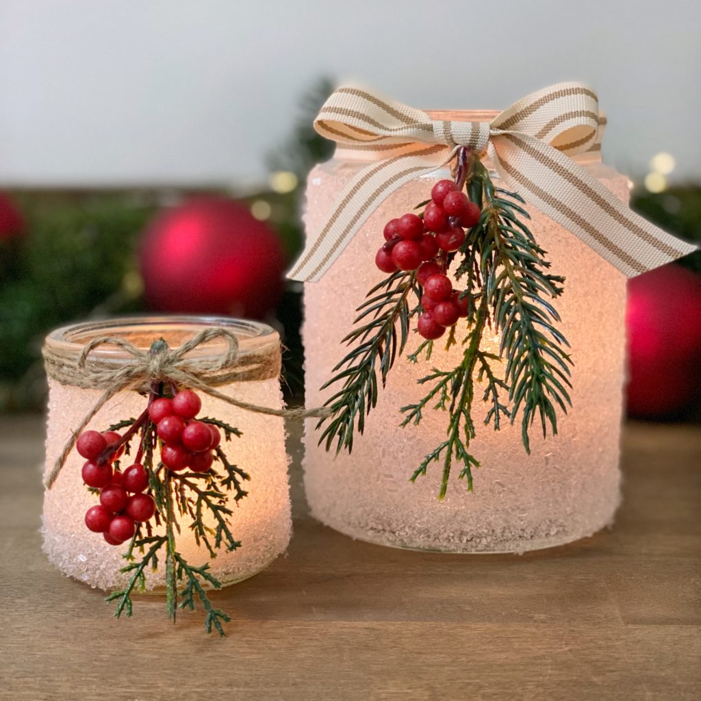 Snowy jar candle holders with the candles lit.