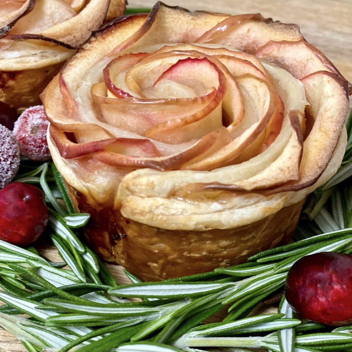 A baked apple rose surrounded by rosemary and cranberries.