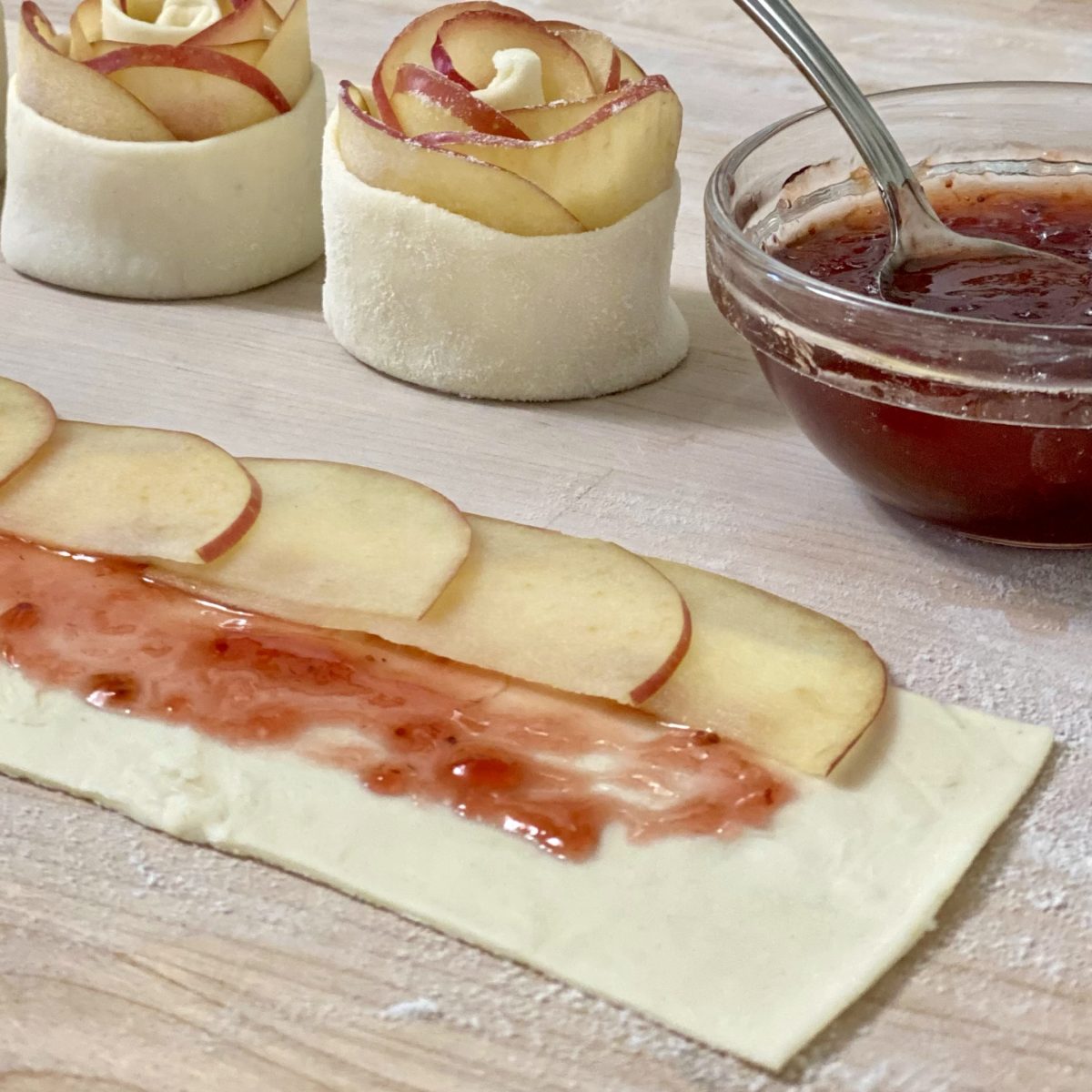 Puff pastry with strawberry preserves on it and apples layered at the top half.
