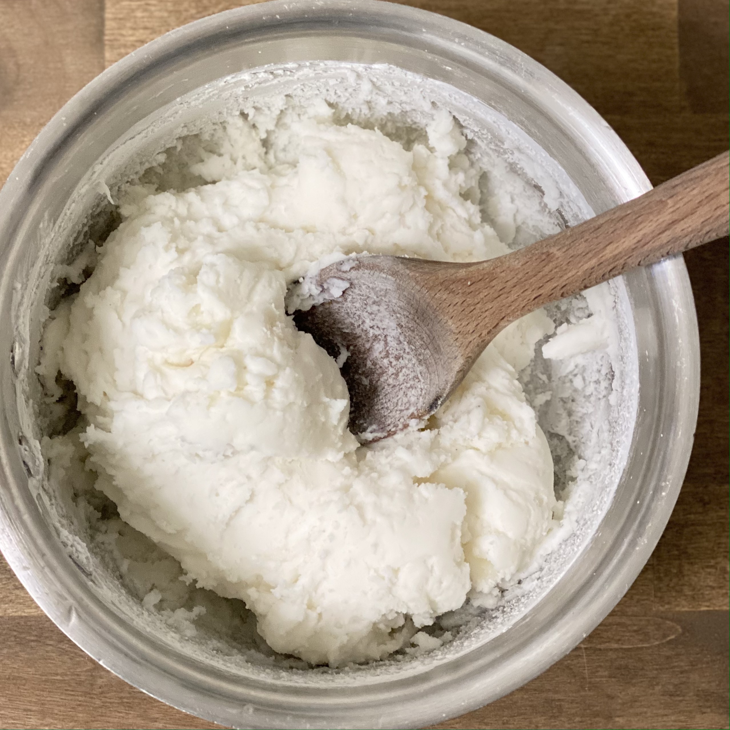 Baking soda dough in a saucepan with a wooden spoon in it.