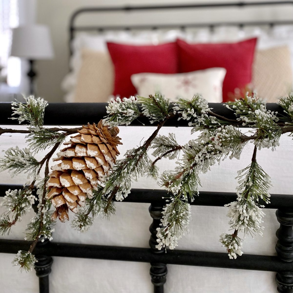 Green garland with snowy tips attached to the foot of the iron bed.