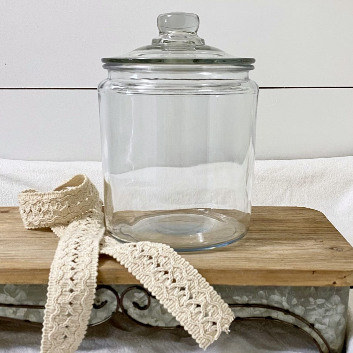 A clear glass jar and ribbon on a riser to make a new year memory jar.
