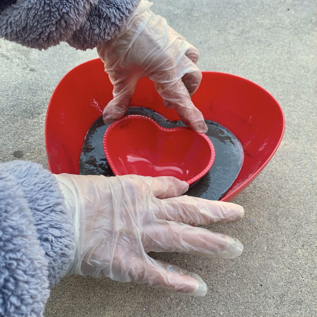 Pressing a smaller heart bowl into the concrete in the larger heart bowl.