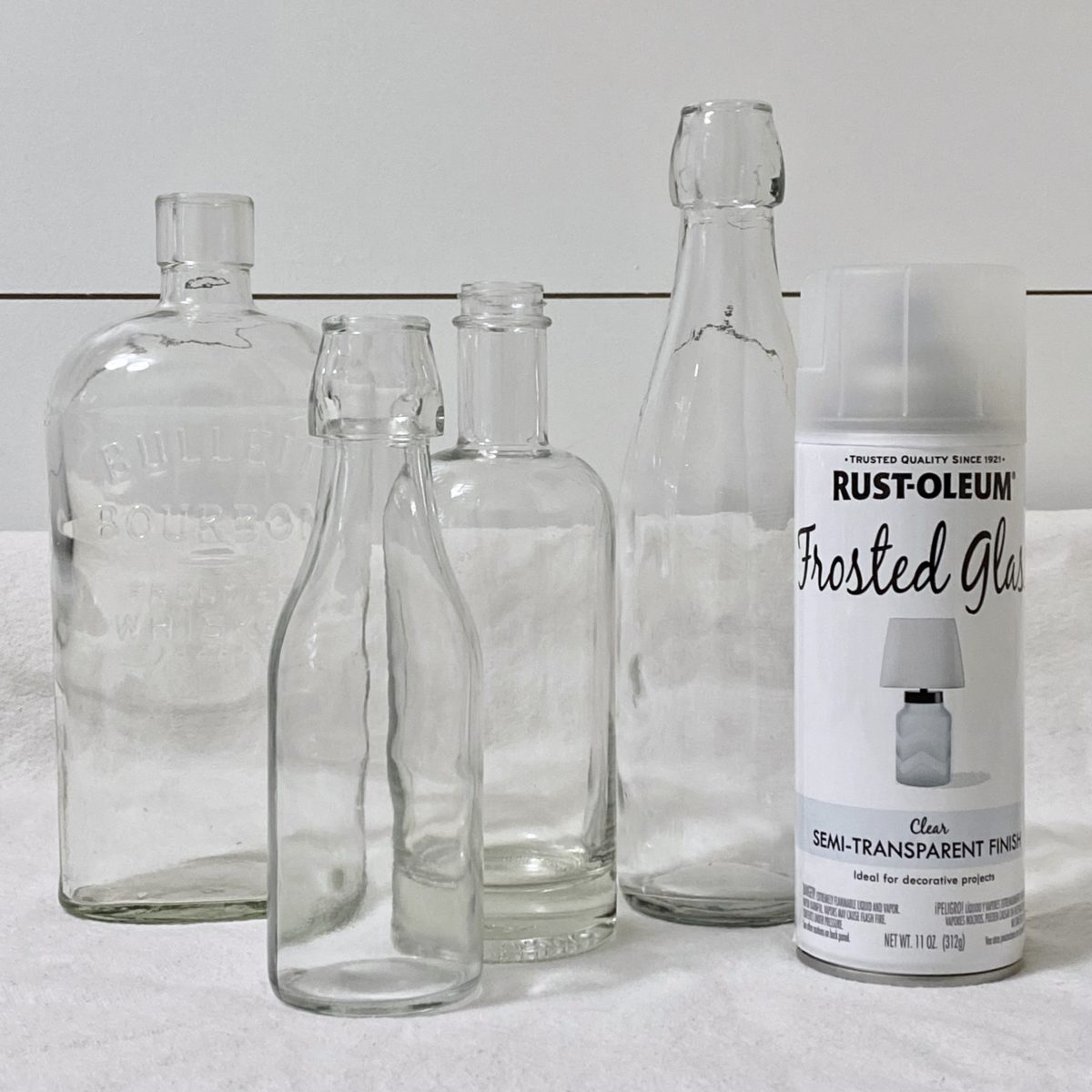 Clear glass bottles next to a can of frosted glass spray paint.