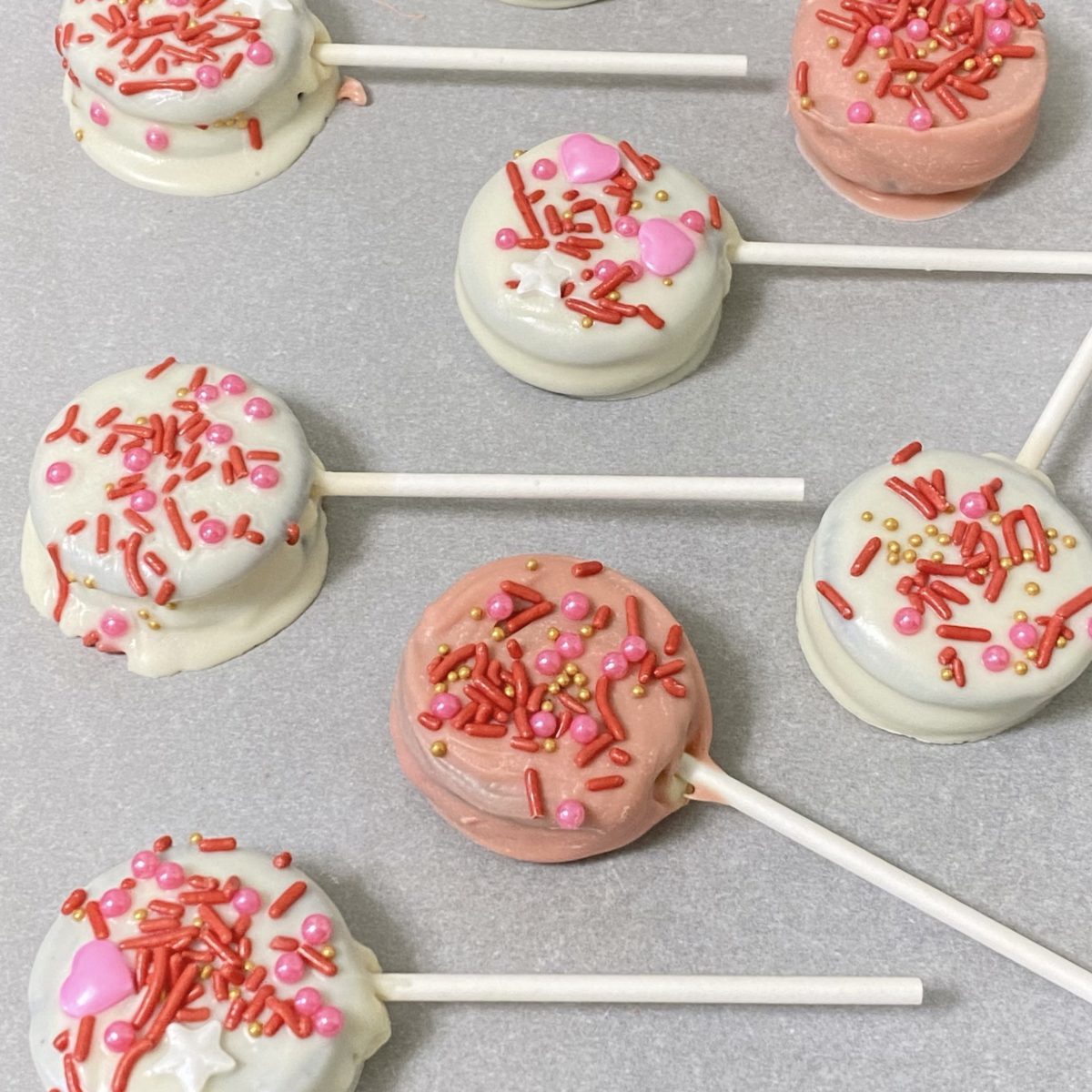 Valentine's Day Oreo pops chilling on a cookie sheet.