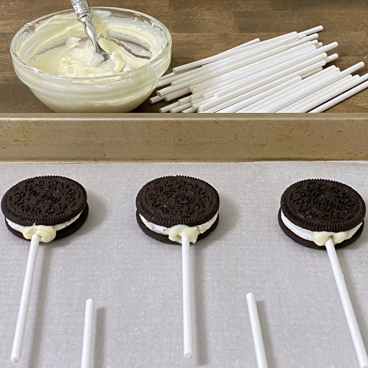 Valentine's Day Oreo pops on a cookie sheet with pop sticks setting in them.