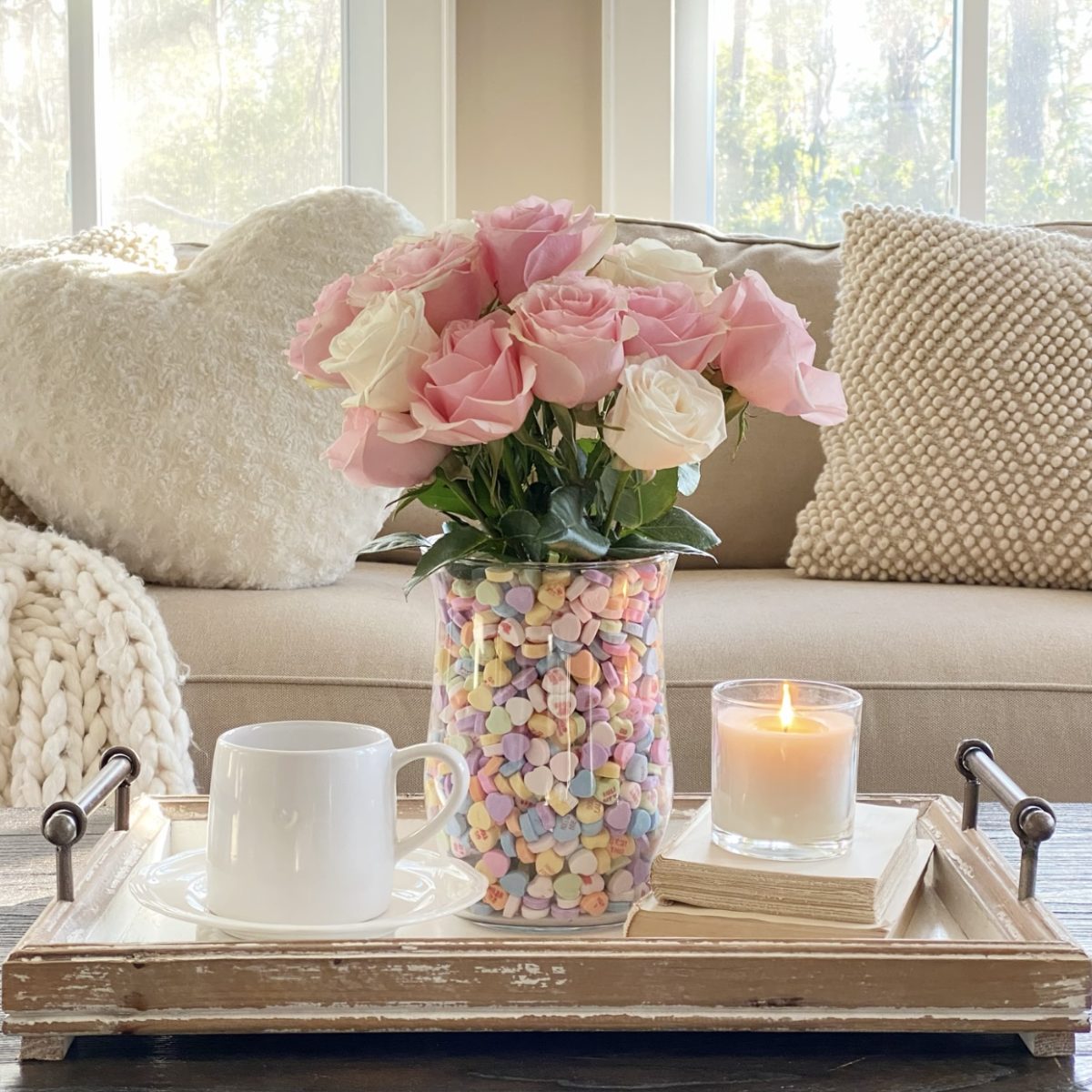 Sweet Valentine's Day floral arrangement on the coffee table with a candle, books and a cup of coffee. 
